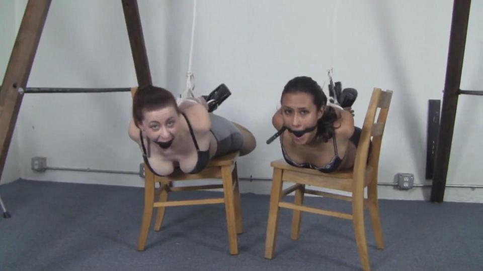 Drea &amp; Serene - Matching Hottskirt Hogties Drea is dressed in a black bra and tight shiny black hottskirt. Her elbows are quickly welded together with thin cord before another rope is grabbed and tightly looped around her wrists. Finally a black ballgag is retrieved and stuffed into her mouth and strapped tightly. Drea is allowed to sit down and her ankles are tied together getting some great views of her black shiny ankles strap six inch heeled pumps. With Drea's bondage completed for now Serene makes her appearance in a shiny silver hottskirt and black bra. Her elbows are welded together first and the same pattern is taken with her wrists being tightly bound next. Her arms bound tihgtly behind her she sits down in the chair and recieves a large black ballgag. Her ankles are bound together and crossed with a loop of rope matching Drea's coming down under the arch of her heels holding her shoes on her feet. Serene is flipped over onto her stomach on the chair she was seated on and a rope is used to attach her feet tightly to her elbow ropes. Drea is then moved onto her stomach and hogtied in a similar manner. Another rope is then used to pull Serene and Drea's hogtie up to the frame holding their hogtie cruelly upwards. Both women are then left to struggle and moan on the small uncomfortable surface in their tight matching hogties.<br><br>https://www.clips4sale.com/studio/33288/7770659/Drea & Serene - Matching Hottskirt Hogties - HD#!Drea-and-Serene---Matching-Hottskirt-Hogties---HD