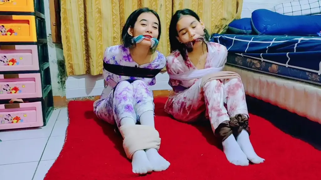 兩個穿著睡衣的女孩用圍巾綁在一起的“睡前遊戲”，比賽誰能最快掙脫。 在一次過夜時，rara 和 ria 決定玩一個遊戲。 他們會用圍巾把對方綁起來，然後比賽看誰先掙脫。 他們真的很喜歡這個遊戲，儘管他們的嘴巴被塞住了，他們還是笑了起來。 喜歡的不要錯過。