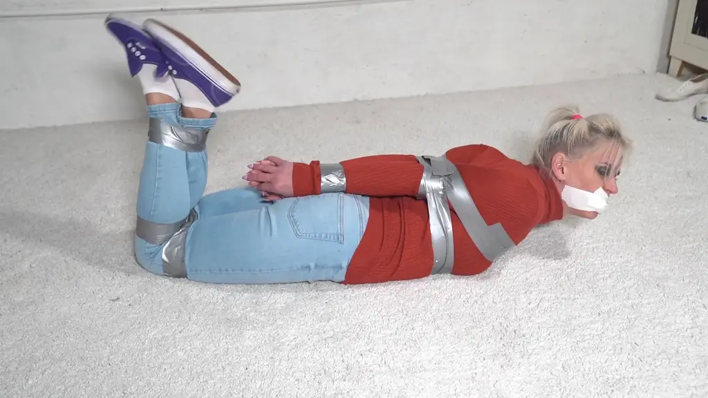 3281 Sandy in Dirty Socks Tape Up wearing jeans and a turtleneck sweater, socks and sneakers, Sandy is taped up. Not only that, a sock is squeezed into her mouth and sealed shut with more tape. Go on, get out!