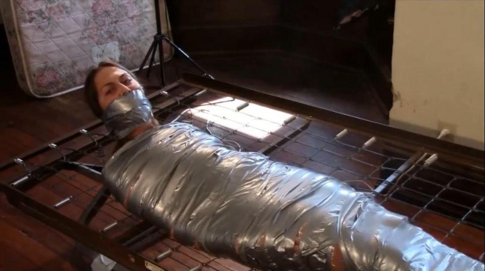 Mummified with whole role of duct tape Mummified with whole role of duct tape. Erica is muffied with plastic wrap and a whole roll of duct tape. She is left to struggle on a steel bed frame. She has bare feet and she struggles and squirms. We asked her to try to roll over while wrapped up so tight, her helplessness is pretty apparent and we gagged her with a sock and wrapped her head with duct tape as well. <span style='color:#b0b0b0;'>[隐藏文字，购买后可见]</span>