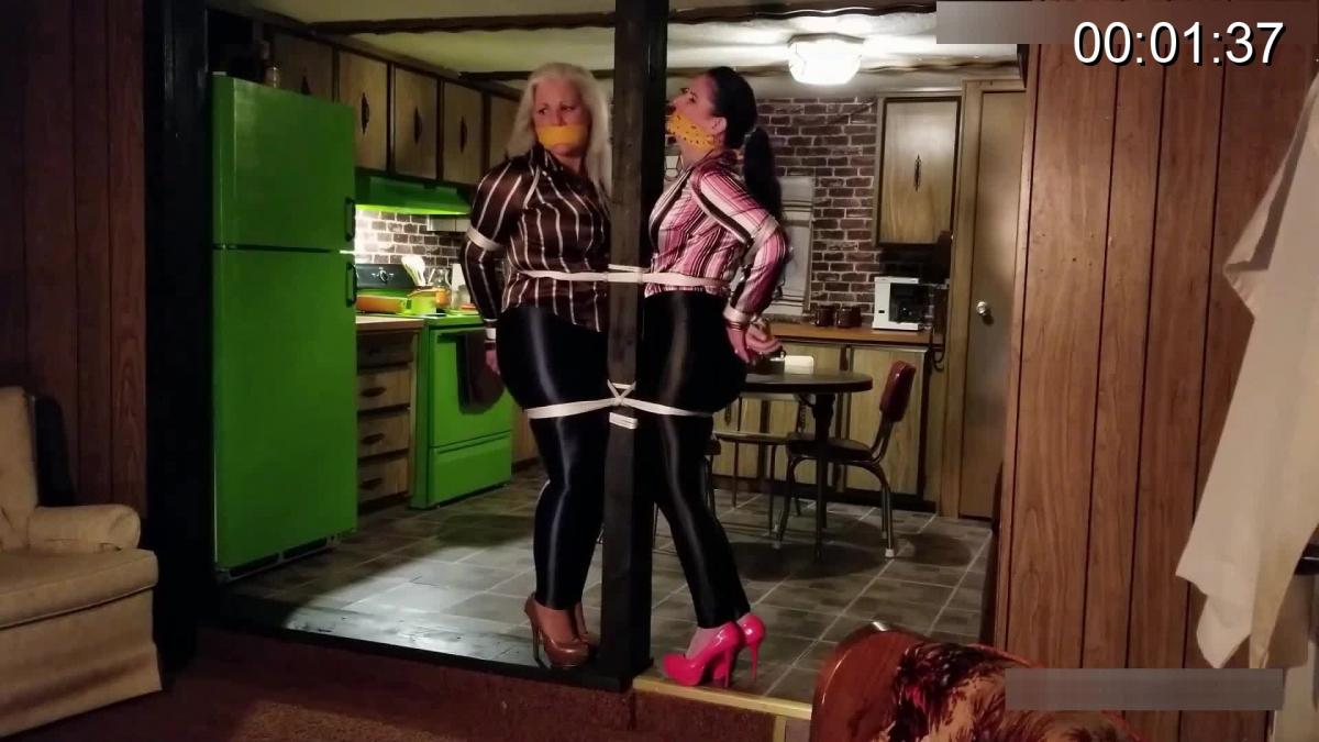 2886 Sandra Silvers, Lisa Harlotte and Caroline Pierce Damsel Duo in Disco Pants Duct Tape Gagged by Burglar After their Record Collection – and an Exposing View of MILF Breasts!<br><br>Shiny spandex and satin striped shirts gleam, as Sandra Silvers and Caroline Pierce stand in their avocado and brick kitchen. Instead of getting their jive on this evening the damsel duo in disco pants has gotten ropes on them instead… Tightly tied together to a pole in their singlewide trailer home! Cat burglar Lisa had heard their record collection was one of note, rock and roll from the 1970s and all the latest tunes, the MILFs being home hadn’t deterred her from retrieving this classic collection of disks, and why not the wood effect record player too. While she’s here she might as well explore the other ample assets that belong to the silver haired broad and her raven locked companion. Two pairs of beautiful breasts revealed from under satin blouses, Sandra’s massive tits in a cream lace brassiere and Caroline’s perky boobs in a fetching floral bra. Before Lisa leaves with her loot she ensures the couple will keep quiet for a while, no shouting to alert the neighbors through their huge bandana mouthstuffings, sealed in with duct tape strips!