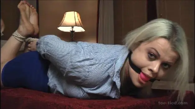 Nadia White Is Cranked And Drooling Here we have the voluptuous Nadia White finally in our clutches!  This sexy and curvy blonde is in a very effective hogtie wearing a short skirt and blouse with high heels.  She's a feisty one as she squirms and complains but this only earns her a nice pink ball cranked deep into her flexible mouth!  She almost immediately begins to drool and continues throughout the video.  Next her high heels are removed exposing her cute soles which are soon joined together by twining her big toes!  This busty hottie is not too happy and cannot escape the ropes as she puckers and gag talks while we take some photos and decide what to do with her next!  Enjoy!<br><br>