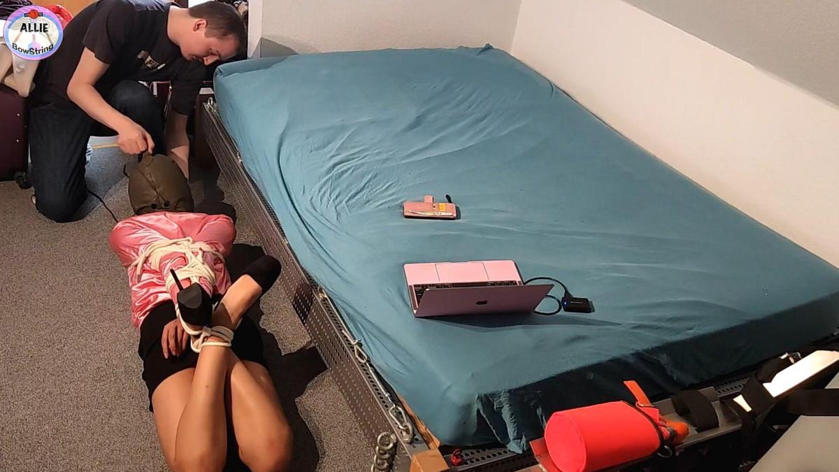 Allie The Hooded and Hogtied Secretary - FULL CLIP Allie the new secretary gurl is back at work! This time, however, she seems to be actually working, as she types on her laptop and finally starts answering her bosses text messages - but this won't last long! Suddenly a man suddenly sneaks up behind her and catches her by surprise! It turned out to be Peter the photographer again, and it actually turns out that he is also a part time damsel collector! He loved how the previous shoot went and now he wants her back - against her bosses wishes. He quickly handgags her and all she can do is say "MMPPHH", but now even this won't do anything as he makes her stop by telling her that he is the one in charge. Panties are stuffed in her mouth and black vetwrap is winded many times around her head so she can't call for help. Allie quickly becomes overpowered and ends up pinned on the floor. Peter grabs the rope, conveniently placed around his neck for easy retrieval and starts by crushing Aliie's elbows behind her back. Now he doesn't even need to tie her wrists yet as her elbows are pinioned behind her back uselessly and fighting back at this point is already impossible, but Allie is sneaky and tries to slip her arms out while the perpetrator is not looking and working on her ankles. However it is all futile as the elbow rope is already cinched, and knotted off. He even ties her heels together for extra style points! Now he cranks up the hogtie tight! It seems like he even studied Jim Hunter's style! Quick and efficient. Allie's own feet are used against her as the harder she tries to kick her feet, the tighter the rope around her chest gets. Even her wrists are tied in the Jim Hunter style. It is a very short rope but it is not short when it comes to effectiveness. A final rope is added to crush her forearms together and add extra security to the hogtie rope that keeps her stuck and immobile on the floor.  Soon the final touch is added, a leather hood to deprive her senses and make her a true captive. He slaps her ass a few times before going to retrieve his van. He even taunts her by giving her mobile phone but takes it away.