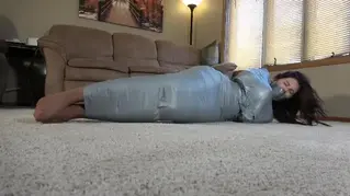Jayme Mummified by Step step-brother - MP4 Jayme is simply relaxing at home minding her own business. Jayme doesn't realize that her step-brother has a prank planned for her as she reads her book. Jayme is surprised from behind and knows she is in trouble but has no idea what he has planned this time. The next time we see Jayme she has been wrapped in duct tape from her shoulders to her ankles! The tape has Jayme's arms and legs pinned tight to her body and completely helpless. As is normally the case Jayme has been abandoned to escape on her own or worse be found and be embarrassed once again. Jayme starts to struggle the best she can in her tight cocoon, rolling on her side and stomach and then back again. 