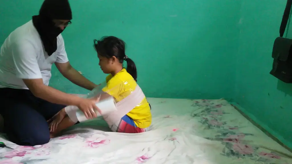 [RM018] Girl was wrapped tightly in a position that it was difficult to move A girl is wrapped tightly in sticky white duct tape.<br>The girls body is wrapped in a sitting position and her hands are holding her ankles.<br>This position makes it very difficult for this girl to move and helpless