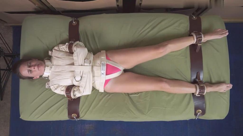 Bedtime for Alyssa Night 艾丽莎·奈特身穿一件特小号的紧身衣，被医院的皮质束缚带绑在床上。她挣扎着，却无路可逃，内心的沮丧与日俱增。从正上方拍摄。Alyssa Night is trapped in an extra small straitjacket and strapped to the bed with leather hospital restraints. Her frustration builds as she struggles but there is no way out.from directly above. 