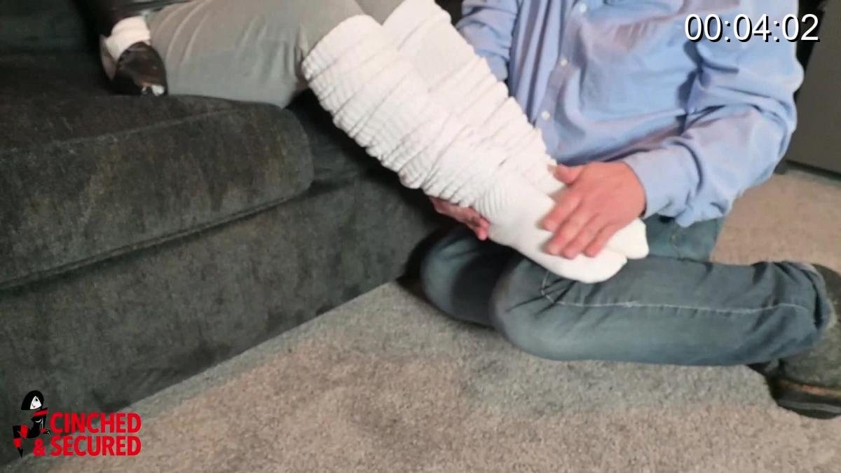 Minx's Massive Mummification When the burglar broke into her home, Minx was secretly excited! She had always had burglar fantasies, but she knew that even though she wanted to be bound and gagged, she mustn't show the burglar her true desires! It was best to go along with everything he said, pretending to be angry at the ordeal. He had taped her upper body tightly, locking her arms at her sides, and now she was about to be gagged! As the packing was pressed into her mouth, she marveled at the size of the mass, and thrilled privately at how well it silenced her! When the man wound black bandage over her mouth to seal it in, and followed that up with sticky, ultra tight black tape, she was sure she would cum right there and then, but she pretended to fight. He left her alone and she struggled in her bondage, wishing the man would return and apply even more tape to her wriggling, squirming body, so she purposely disobeyed his instructions, moving about the room as she pretended to look for a means of escape. Sure enough, the man returned and grabbed her from behind, clamping a hand over her gagged mouth! Now with her ankles bound, she squirmed on the couch, wriggling her feet and reveling the way her heavy socks felt as she did so. Still, she had to have more, so she slowly made her way throguh the home and up the stairs into the kitchen! "Caught" again, she now found herself mummified from head to toe in more of the sticky black tape, this time fused to her kitchen table! Next to her was her cell phone, and she tried to reach it to call a girlfriend, knowing how happy her friend would be for her! Her noises attracted the burglar yet again, and soon she was wrapped in a heavy blanket and left squirming on the floor! Her movement massively restricted, she bucked like a fish, but this time she was truly helpless! As she wiggled her sock-clad feet, she was in ecstasy! Now the burglar was finished with his chores, and the only thing left was to ensure that Minx could not escape and alert the police, so he wrapped her from head to toe in the black tape! Now, left alone to strain and squirm in the ultra thick cocoon, Minx girl was in heaven!