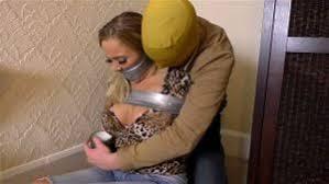 Beth in: She Was Hidden Upstairs in the Stage Make-Up Room Struggling Furiously While 'Arrangem Beth in: She Was Hidden Upstairs in the Stage Make-Up Room Struggling Furiously While 'Arrangements' Were Made... (Full Caper) (HD)<br>(1280x720) (HD) <br>Beautiful blonde native New Zealander Beth is, like so many others of Borderland Fame, an intense and fierce struggler, who really resists being trussed and gagged. Of course, this makes it all the more satisfying to her into inescapable predicaments, knowing that she is doing her best to fight it. The only thing that will fully contain the busty bimbo, we feel, is a ton of the strongest tape around. Let’s get her!<br>Gorgeous gumshoe Beth has been tied up in an office chair after getting caught trying to access some pertinent and highly dodgy sales order files on the office PC. Naturally, she is caught, handgagged and bound up and kept quiet. We’ll show you all of that, so fear not, but the real deal here is the extreme taping and huge stuff gagging she is about to receive after being shoved, wrists still tied, former gag hanging around her neck, up a flight of stairs and secured good and proper in  back room. That’ll fix her…<br>It’s a supposedly out of business theatre company she has been investigating, which by all outward accounts ceased trading back in the nineties – well, at least legitimately. Now it still goes under the same name of Gosling & Signet Productions Ltd but the only stuff passing through its coffers is dirty money. Yep, they haven’t so much as performed a single Winter Panto since 1998, so what are they up to instead? Well, inquiries have led the tight jeans-clad beauty to suspect they are importing illegal trophies and trinkets from African islands and selling them for ludicrous profits to collectors who once used to be their clients. Apparently, despite enjoy a good show, they also enjoy benefiting from the proceeds of crime. Scum! Beth’ll stop ‘em.<br>The saucy sleuth is right on the money, literally, and the crooks behind it all, led by Ex-Vaudeville artiste Jeremy ‘The Whinger’ SlushBucket, will be tarred and feathered if they are about to allow this buxom young madam to interfere with their decades long scams. So, we now know she has already been nabbed. We know the underling who has her under control has informed his boss of what he’s caught sniffing around, and we know that the evil (and he really is) SlushBucket will no doubt have something rather unpleasant lined up for the damned meddler when he visits the old place later. For now, the orders are to secrete the girl upstairs. The underling is to use the old make-up room for the purpose…<br>Roughly marched up a gloomy flight of steps, Beth, asking what the fiend is planning, is met with a good taping of the wrists and ankles. Before she can object too much more, the guy gags her again, this time by removing her cute little sneakers to get at her socks, which he peels off and stuffs, we can only describe as ‘violently’, into her mouth. He’s heard more than enough out of this one, despite her having one heck of a cute accent, the Kiwi witch.<br>Her face heavily, heavily bound mouth and head alike with a lot of silver tape, the eye-bulging, involuntarily gagging and mmmppphhhhing hottie is left stashed in a corner of the room, parceled up, barefoot and utterly helpless. She tries to do a lot of things in her efforts to escape, including attempting to topple a heavy wardrobe filled with old props. She can’t budge it though and this frustrates her massively. She was hoping the sound of it crashing over might bring some attention from the street below. Maybe she can get to a window instead…<br>She slithers around on the floor but quickly realises that she is bound way too tight to even crouch. Her legs are completely packaged. She can’t get the height… and so she continues to struggle wildly, showing off her shapely bare feet, feeling the cold on them. Where are her… Oh yeah, they’re stuffed deep into her fucking mouth! Aaarrggghhh she goes nuts again but just then she notices the door has been left open, after the pervert who has her up here has just left having helped himself to her tits! She does a quite unique shuffle in that direction but is intercepted again. Seems decisions are being made about what to do with her, and she does not like the sound of any of this.<br>Alone once more, a secret captive indeed, She’ll have to find some other way to get out of here. Gagging on her socks, shrieking (wonderfully muffled) into her severe face gag, we can but wonder, in awe, what that might be. But the headline news here is that this is super gagged up Beth on steroids, so in the meantime, so miss a single jaw-dropping second!<br>***All productions (video & images) & associated bondage scenarios depicted are strictly of a role play and story driven nature and feature fully consenting participants and established safe signals (clearly defined within each fantasy scene) between model(s) and crew are in continual use throughout the production.  Thus, these are pure, tongue in cheek adventuristic fantasy scenarios, without exception fully consensual, contextual and supported by model release to this effect***
