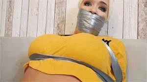 Lila in: A Danger-Laced Assignment &amp; a Beautiful SpyGirl Fighting the Tape Like a Warrior-Prince Lila in: A Danger-Laced Assignment & a Beautiful SpyGirl Fighting the Tape Like a Warrior-Princess! (HD)<br>Stunning, buxom blonde Lila is like a leaping salmon – a beautiful warrior against the tape which restrains her. This babe really goes for it, testing our bondage mettle, and the villain of the piece wraps her up so securely she’s fit to burst. See how the bothersome little meddler deals with THAT!<br>It’s a case which has haunted them for a while. A demented political saboteur has been rigging elections and funneling large sums of cash to a hostile regime (so, not too much then…) but until now, all leads to him have been erased. Somebody, somewhere, is covering for him… Enter a lovely female SpyGirl who knows how to work a hot tip or eight, if you’ll allow us this? Not sure how much danger she faces, the intrepid chick nevertheless engages in a bit of recon.<br>Having entered a house pinpointed in her informant’s brief, she decides to snap as many pictures as she can and leave, to return another day, once the data is analysed. Thing is, somebody bad is here NOW (the saboteur Himself, in fact), who will do all in his power to prevent the comely maiden, in her tight jeans and cropped t-shirt, from returning another day!<br>Sneaking up behind the lovely snoop, preoccupied flashing away with her camera, a masked villain accosts her fiercely (Lila puts up a big struggle in this, and brings her to ground long enough to truss her wrists behind her with silver tape. Next up, he decides to gag her. He’ll use her own socks to stuff her mouth - plucked straight from her warm feet! While Lila bitterly protests, the creep, having none of it, shoves the socks into her mouth and really goes to town on her, packaging her lower face and head to the maximum with tape!<br>Utterly dummied up, Lila seethes with rage. The dude is going insanely hard but there is nothings she can do about it. The assailant continues to bind a heavily/superbly muffle The sexy spy with more and more tape, banding her up like a pork loin The huge gag prevents her from objecting orally so she kicks and bucks but he overpowers her with his brute strength.<br>Clearly enraged with this spy bitch who would see him imprisoned, the political psycho leaves the firmly gagged and bound beauty to struggle, which is something Lila does with huge energy. Lashings of super-hot, barefoot hi-jinks sense with our comely hottie first bound up at the table and then rolling and bumping around and all across the floor, spasming up like that salmon leaping we mentioned earlier and thought was a cool analogy!  We think she’s trying to find something sharp. But she cannot and so goes right back to bouncing around, electrified with panic and tension.<br>The gurgling and muffled beauty is indeed parceled up like a prize sausage! Gag talk here is first rate by the by, as per, and the babe flops about all over the hardwood floor. Wonderful to watch. Lila, despite her craziest efforts, is utterly incapacitated.<br>After a time, the gagged up, mumbling and groaning hottie makes it onto their side and eventually onto a couch, where she writhes about utterly secured and monstrously muzzled by her huge packed out silver gag. They don’t get more brutal than this, either. Wriggling and bucking away on the couch, the well- wrapped babe is taunted by the crook, who even goes thrugh her handbag for info against her. Then its toe pointing and sole scrunching time as all that great foot fetish stuff comes into play.<br>Having been felt up and mauled in general again, the bound babe gets abandoned again to writhe and strain at her tape. No one ever has escaped it, by the way, and Lila, in spite of her very best efforts, is no exception, but does she ever try, for our huge amusement!<br>Meanwhile, the saboteur is making plans for a very fast flight, highly amused by the occasional thud from directly below him as the tightly gagged and bound Lila thrashes around in earnest. The captured spy gal is going berserk, furious at the excessive way she is bound. She can’t so much as loosen this stuff and just hopes that one of the team will check the case logs and found out where she was headed today. Bound and gagged like this, so extremely, she has but one hope she will be rescued, before the saboteur does what he does best, this time with her own ass on the danger-line! Bbbbbfffmmmm!!!<br>***All productions (video & images) & associated bondage scenarios depicted are strictly of a role play and story driven nature and feature fully consenting participants and established safe signals (clearly defined within each fantasy scene) between model(s) and crew are in continual use throughout the production.  Thus, these are pure, tongue in cheek adventuristic fantasy scenarios, without exception fully consensual, contextual and supported by model release to this effect***