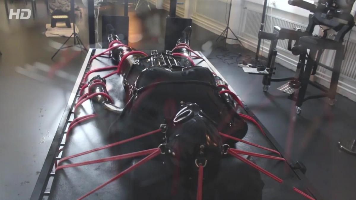 Bondage Helmet - Part 3 This week I was with Comtesse Larissa at then new and really awesome equipped new dungeon in Zürich, Switzerland, called "Der FemDOM". We give our visits mostly some pervy name and so we called it this time "Rubber Mania" and finally this was also on the schedule...<br><br>… we arrived monday morning in Zürich and started to unpack fastly our luggage and rubber because we were really short on time and had to rubberize ourselves and prepare everything for the session. I helped first Comtesse Larissa into the big boobed catsuit and so it happened that we already find ourselves while dressing up in the session, even if the guest wasn’t still in the dungeon.<br><br>I was dressed in my black lockable rubbercatsuit and as always I had to rubberize my crotch in a really pervy style. After that I was laced first into a black COR13 corset from HW-Design and another rubberpussy was attached between my legs. Double rubberpussy! This was even new to me too  but the feeling was incredible sexy and horny.<br><br>The real thing started after the corset. The Bondage Helmet. An integrated heavy rubber mask and neck corset, which can be added to the straps of the COR13 corset. It laces from top of the head to the complete end of the bondage helmet is therefore very restrictive and tight. Larissa had certainly a lot of fun squeezing my head into this rubber head prison and strapping it to the corset then.<br><br>She watched on her work and let me turn one time to see the complete beauty of this restrictive outfit. Then she started to rub my double rubberized pussy in my crotch, when she realized that the guest has written a SMS telling that he will be 2 hours late because of heavy traffic jam. This was the moment, when Larissa became a horny and breathtaking plan. She put me for this time into the gibbet cage. Fully laced and corseted as I was, I was put into this almost tight and unbreakable metal stand prison…