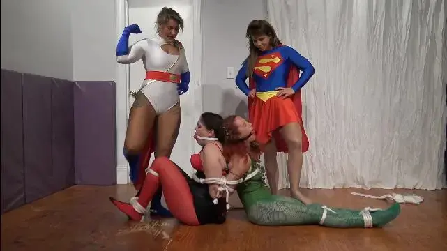 Superheroine Capture Scheme! Sheena, Warrior Amazone, VeVe Lane, and Katarina (1080) Visiting wrestlers Sheena and Warrior Amazone get decked out in shiny superheroine spandex as they jump in to take down a pair of wily villainesses in this little bondage caper:<br><br>Poison Ivy and Harley Quinn (VeVe and Katarina) have hatched a plan to capture their super-strong foes Super Girl and Power Girl (Sheena and Warrior Amazone).  Afterall, there's nothing like a little carefully-placed kryptonite to weaken a Kryptonian!  <br><br>Ivy and Harley lure Super Girl and Power Girl into an ambush, where they capture our virtuous heroines in a kryptonite-laced net.  Oh no! -- with the kryptonite sapping their powers, Super Girl and Power Girl are helpless to resist as the villainesses wrestle them down, torment them with punishing holds, and complete the heroines' humiliation by binding them into hogties (no gags).  After slipping kryptonite necklaces onto the captured Kryptonians, the villainesses leave their shiny-yet-powerless superheroines to struggle in their bonds, confident that they will never be able to break free.  And, indeed, despite their wiggling and squirming, they cannot!  Oh, alas, to be without super strength!<br><br>
