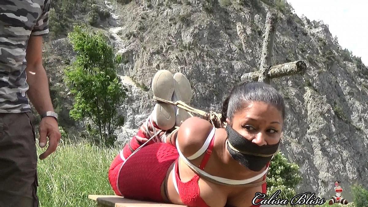 Calisa Bliss: Hogtied in the Swiss Alps During my time in Europe I was tied up in Italy, Germany, Spain and Switzerland! In this video I am hogtied by Mario in the Swiss Alps! It was dangerous and difficult to get to our destination. It was also forbidden, so we would have been in so much trouble if caught. First he ties my legs and arms super tightly with Spanish Rope. Next, he lifts me up and puts me on a desk we found in an abandoned cabin. It was very unstable so I had to be careful. Luckily, Mario hogtied me very tight so my struggling would be lessened. I was so excited when he finally stuffed a large sponge into my mouth and sealed it in with vetwrap. He even added rope as a cleave gag and tied it to the hogtie along with my hair! I had the best view and an audience of Sara Brooke and Sasori! Outdoor bondage is my favorite!