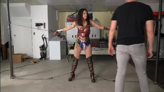 Wonder Woman (MP4/M4V) - Jasmine St James The villain of the piece, Viktor Drack, is planning to place devices at a nearby reservoir and dam, both of which will break open and spill a deadly poison into the water supply later that day. Millions will die if no one stops him. It’s a good job Jasmine Prince has got wind of his diabolical scheme! She visits his woodland hideout and begins to search the basement for any sign of the devices she believes Drack plans to use, and exactly where he plans to plant them. She inadvertently walks into a trip wire and releases a knockout gas. Before she realizes what has happened, Jasmine inhales the gas and, despite her valiant effort to get to the door and fresh air, she passes out.<br><br>When she wakes, she finds herself bound to a chair, her wrists and ankles secured with thin zipties. She struggles in an effort to free herself but can’t break the ties. Soon, Drack appears to taunt her, explaining that he would love to stay and watch her struggle, but he has places to be, devices to plant. He tells her about poisoning the local reservoir, and chuckling to himself he leaves his captive alone, with no idea who she really is. With time running out, Jasmine fights even harder against her restraints, so desperate to stop Drack that she manages to transform into her alter ego, Wonder Woman. Now, if she can only get to the reservoir in time.<br><br>