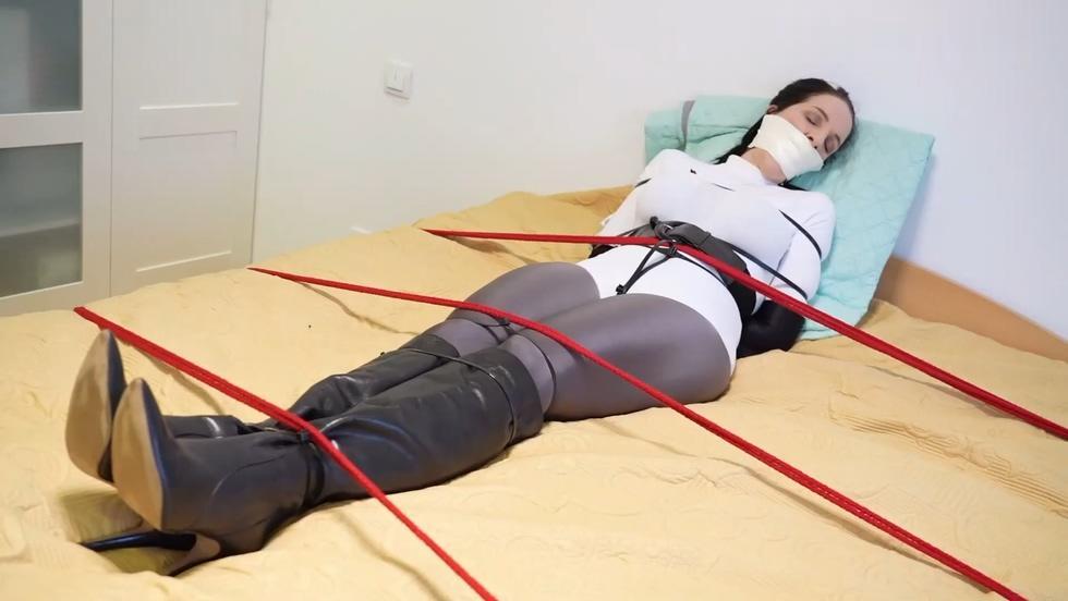 PAULA SUPERHEROINE ZIPTIED AND TAPEGAGGED 超级女英雄保拉正在调查一个房间，但却被一个穿着皮衣的恶棍制服了！ 宝拉现在被黑色拉链绑在床上，她的球口用多层微泡沫胶带固定Superheroine Paula was investigating a room but got overpowered by a leather clad villainess! Paula is now tied on a bed with black zipties and her ballgag gets secured with layers of microfoam tape