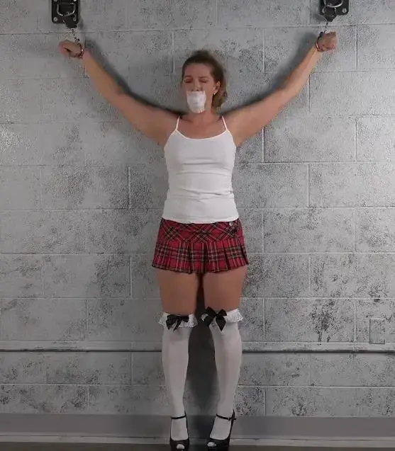 ERIN: HANDCUFFED AND TAPE GAGGED SCHOOLGIRL 可爱的女学生艾琳被铐在墙上，双臂张开，嘴上贴着白色的医用胶带。 她试图说话并哭泣寻求帮助，但除了压抑的抗议之外，她无法做到更多。 一个可爱的女孩，真正的无助和沉默。Adorable schoolgirl Erin is cuffed to the wall, arms stretched wide, with her mouth taped with sticky white medical tape.  She tries to speak and cry for help, but is unable to manage more than muffed protests.  An adorable girl truly helpless and silenced.