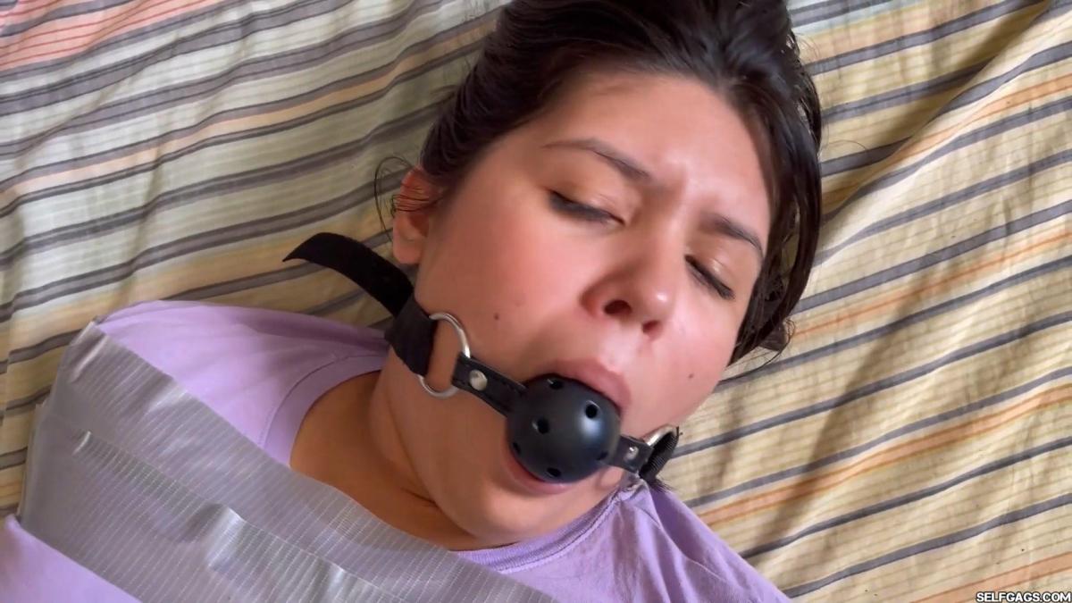 Tape Bound Mary's Ball Gagged Bondage Struggle Mary wakes up ball gagged in tight tape bondage on a bed. She doesn't know where she is, why she is bound and gagged, or who tied her up.<br><br>The helpless girl starts to struggle to try and escape her tape bondage, but it is much harder than she thinks it is. The tape restraints are holding her hands, arms, and legs together really tight and it is going to take a lot of energy and effort to escape!<br><br>Mary frustratingly squirms and whines in anger as she realizes how hard it will be to get free. It becomes certain to her that she is going to need someone else's help to free her. She moves her tape-bound body down on the floor where she works her way out towards the stairs.<br><br>Mad, helpless, and desperate, the barefoot bondage girl gets her tied body downstairs. She manages to get on her feet and hops towards a door that turns out to be locked... Determined to escape, she heads towards another door. It opens and out she jumps!