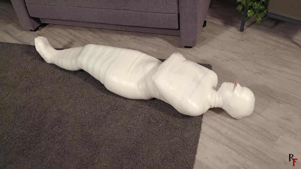 Patty in total microfoam mummification Part 1 - A tight cocoon instead of a date (UHD 4K MP4) The charming Patty, at home in her underwear and tights, is getting ready for a date and is applying makeup in front of the mirror. Suddenly, she is caught by a rigger who ties her up with white microfoam tape. Patty ends up on the bed, her hands tied behind her back, her legs tied at the ankles and thighs with tape, and her mouth also sealed with tape. She struggles and manages to get to her feet, she tries to hop away, but the rigger is right there, holding a bag with a lot of white tape.<br><br>The rigger thoroughly wrapped Patty in dense white microfoam tape, covering her entire body and leaving only her nose for breathing, then left to fetch his friend, leaving Patty alone in her room in total mummification.<br>The beauty struggles and tries to do something, but the tape's embrace proves too tight. Patty is first on the couch, then slides off it, crawls on the floor but can't free herself, appearing from the outside as a cocoon with delicate prey inside.<br><br>Eventually, the trigger and his partner enter her apartment. They inspect Patty's bondage, make some adjustments, and then, one grabbing her legs and the other her shoulders, they carry her away somewhere… To be continued.<br>Enjoy!