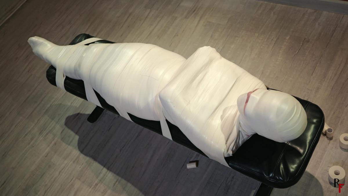 Patty in Total Microfoam Mummification Part 2 - More Secure Fixation to the Bench in the Dungeon (UH Patty in Total Microfoam Mummification Part 2 - More Secure Fixation to the Bench in the Dungeon (UHD 4K MP4)<br>This clip is a continuation of the first part:<br>Patty in total microfoam mummification Part 1 - A tight cocoon instead of a date (UHD 4K MP4)<br><br>Two riggers brought the cocoon with Patty fully mummified inside into the dungeon and threw her onto an old dirty mattress.<br>Patty desperately struggles in microform tape and tries to escape from the tight embrace of the wrap but to no avail.<br>She growls, moans, jerks, and rolls from side to side, and from her belly onto her back, but she can't manage to free herself. A lot of struggling doesn't help her to escape.<br><br>The two riggers approach her again. One picks her up, while the other removes the mattress and places a bench. The riggers then tie mummified Patty to the bench using the same material she is completely wrapped in. After, the riggers leave and she is left in complete solitude in the dim dungeon.<br>The beautiful Patty still tries to escape, but her body is overtaken by fatigue, and she gradually resigns to her fate of being a captive doll in a tight microfoam cocoon.<br>Enjoy!