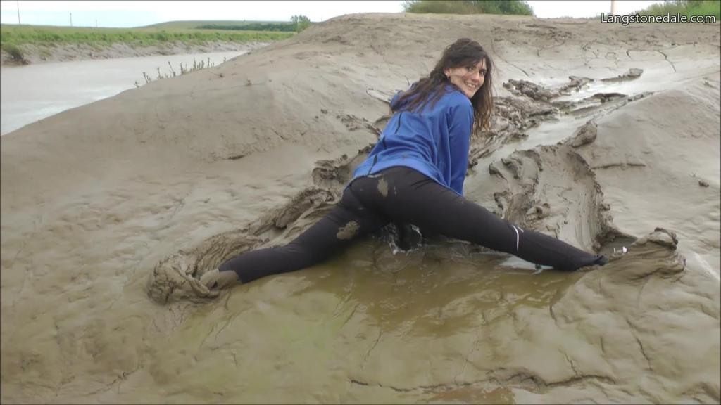 Maude's mud workout Maude is dressed for exercise, wearing skin tight black ladies running trousers over a black and purple swimsuit, with running shoes and a blue Bench branded full-zip hoodie. She walks into the mudbanks, and after a few minutes of trying really hard to stay upright while performing a variety of athletic poses, showing off how flexible she is, eventually she gives in to the temptation and lets herself fall into the mud, splat, several times!<br>Steadily she gets muddier and muddier, first the back of her trousers, then up to her knees, then from crawling she presses her front into the mud. Part way through the jacket comes off so we can enjoy a clearer view of her trousers and swimsuit succumbing to the mud, once the rest of her clothes are totally coated she puts it back on and utterly mud-drenches it too.<br>Needless to say her hair doesn't escape the muddy mayhem, and she gives herself a spectacular mud facial as well!<br><br>--Langstonedale<br><br>莫德穿着运动服，在黑紫色泳衣外穿紧身黑色女士跑步裤，搭配跑鞋和蓝色全拉链连帽衫。她走进泥滩，经过几分钟的努力保持直立，同时摆出各种运动姿势，展示自己的灵活性，最终她屈服于诱惑，让自己掉进泥里，溅了好几次！<br>她慢慢地变得越来越泥泞，先是裤子后面，然后一直到膝盖，然后从爬行开始，她把前面压在泥里。夹克脱了一半，这样我们就可以更清楚地看到她的裤子和泳衣被泥浸湿了，一旦她的其他衣服都被完全裹上了，她就穿上它，把它完全浸湿了。