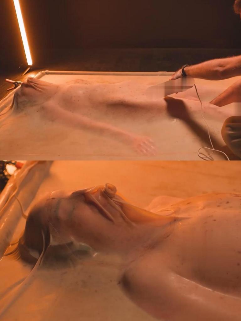 Rosie Lynn in vacbed 罗西·林恩 (Rosie Lynn) 走近真空床，戴上耳罩以进一步剥夺感官，然后滑入其中。真空床完全固定后，打开真空，将空气从床上吸出，将她困在原地，尽可能不动，被橡胶乳胶包围，她无法逃脱。日立振动器放在她身上，在她被困在真空床上时不断刺激她。Rosie Lynn approaches the vacbed, puts on ear muffs for further sensory deprivation, and slides inside.  Once fully secured with the vacbed shut, the vacuum is turned on, the air sucked out of the bed, trapping her in place with as little movement as possible, surrounded by the rubber latex with which she cannot escape from.  A Hitachi vibrator is on her, giving her continual stimulation while she remains trapped in the vacbed.<br>