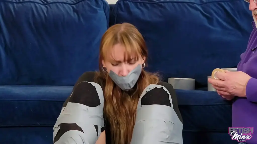 1656 - Cara's Tape Tied Workout Cara had just finished her workout when she was captured by a creep. Now, her legs spread wide and her arms and wrists taped to each of them separately, the poor girl is completely helpless, her modesty preserved only by her workout clothing and pantyhose. Worse still, her protesting only succeeded in getting her mouth packed, taped and sealed over with a tight vet wrap gag!  Now she's really doomed! As she writhes about the room, flailing about and moaning into her gag, she cannot help but put herself in some very comprising positions. Ass up, on her back with legs spread, no matter what she does she presents a very luscious feast for the eyes, and with her assailant still there, it's only a matter of time before he takes what is now his!<br><br>