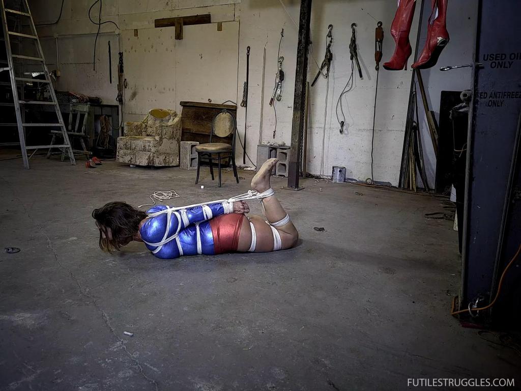 Carissa Dumond's Ultra Girl Fantasy - Part 6 Ultra Girl ends up tightly bound on the concrete floor. After a while, Dr Cupcakes decides that she has too much movement for his liking, so her hogties her