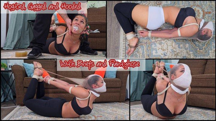 Calisa Bliss: Hogtied, Gagged, and Hooded with Briefs and Pantyhose Calisa is minding her own business, finishing her housework when an intruder grabs her from behind. She is shocked and immediately struggles against the man but he's too strong. He easily pulls her wrists behind her and starts tying them. This leads to Calisa being fully hogtied at the Intruders mercy. She wiggles around on the ropes wondering what's next. All of a sudden her head is yanked back by her ponytail and two socks are shoved into her mouth. The intruder then starts wrapping clear tape around her head to ensure she can't spit the socks out. But the intruder isn't done yet. He not only puts a pantyhood over Calisa's face, but he also pulls a pair of pantyhose over her head as well, pulling them back to tie to her feet. Calisa is furious. She's moaning and bitching through the gag, struggling in the ropes and trying to stretch the pantyhose enough to allow her to rest her head but it's not working! She keeps fighting, but her energy is obviously fading over time. There's no telling how long she'll be like this!