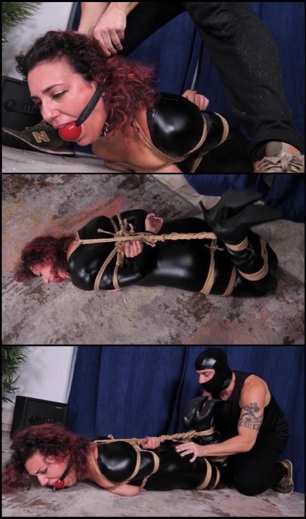 Bondage wrong palace The sexy Saudellian beauty Bambi is a professional burglar; he waited lot of time to put on her sexy leather catsuit and her leather boots and sneak, in the middle of summer, into this almost uninhabited palace where the owners have gone away for the summer holidays; after robbing the first two apartments, Bambi enters the one on the second floor, at the moment not finding anyone in the building he did not need to use ropes and tape to immobilize some of the owners. The sexy kitten is sure that even for this apartment it will take a few minutes; entering the room she notices something that surprises and amuses her; bunches of rope on the floor, and a comic book with women and thieves like her tied and gagged with meters of rope and tape. Bambi thinks what a strange joke this is, she thinks probably she is at the house of a pervert, she thinks it's better to move because the evening is long and after the hit she would like to go out to celebrate about the loot;  the kitten, however, has not reckoned with the owner, a muscular and masked man who grabs her from behind, shoves a huge sponge in her mouth, closing it with pieces of tape and then begins to tape her massively; Bambi is strong, she tries to wriggle furiously and scream, but she is immobilized in a very short time, in the fight her catsuit also got unzipped and now her exposed boobs catch the attention of the masked man who begins to grope her heavily, while the sexy thief moans a flebile mmmmpphh; the satisfied man leaves the thief to wriggle in the living room,  Bambi does not believe that this could have happened to her, who came to steal and possibly tie and gag the owner on duty, now she finds herself tied gagged humiliated and sweaty on a sultry summer night; the kitten struggles furiously so the masked man comes back and gags her even more heavily, telling her that they will spend the weekend together, the ropes that Bambi has the honor of seeing close to her on the floor in a while will be tightly cinched around her sinuous body and that huge mouth of hers is made to contain something extremely big; poor Bambi, her sweet eyes convey all the concern for a home invasion more complicated than she thought. 