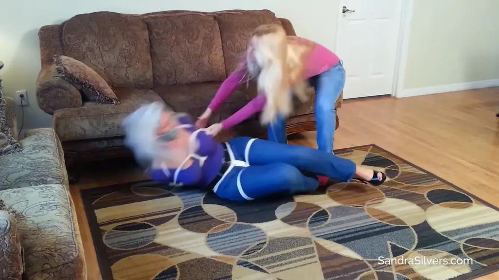 1741 - Sandra Silvers, Lisa Harlotte Sandra fights Lisa all the way when the curvy MILF is set upon by the lithe blond. Sandra can't call out, thanks to the duct tape sealing her mouth shut, but doesn't stop her from mmmmphhhing and pleading through her gag as Lisa adds the finishing touches to this big-titted broad. Sandra has no intention of making Lisa's job easy, energetically bucking and resisting the whole way. so much so that at one point, Lisa sits on her captive to keep her still as the ropes go on!