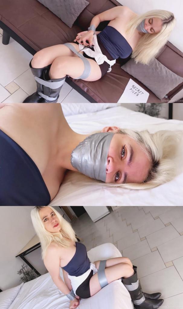 Mission FAILED?! Heroine Nani Gets TAPE-GAGGED for Snooping Enemy Base!  当吉尔·瓦伦蒂安进入安布雷拉的秘密基地时，她做梦也没想到自己会被捆绑起来，嘴巴被塞满胶带封住！<br><br>我们的女主角娜妮（化名吉尔·瓦伦蒂安）潜入敌方基地，寻找能够揭露安布雷拉秘密的秘密文件。“我找到了！就是这些秘密文件！现在……嗯……”娜妮的喜悦戛然而止，一名安布雷拉特工一把捂住她的嘴，把她扔到床上。<br><br>“你休想得逞！”她喊道，却被胶带紧紧地绑在背后。她穿着光滑皮靴的美腿也很快遭遇了同样的命运。“我要把安布雷拉的秘密公之于众……嗯！”她英勇的宣言戛然而止，蒙面入侵者将一块柔软的白布塞进她的嘴里，让她无法发出声音。特工精准地将布料塞得更深，彻底堵住了她的嘴，让她发出的抗议变成了可爱的呜咽声。<br><br>为了确保她被堵得严严实实，蒙面男子在她塞满东西的嘴上贴了几条胶带，用力按压，确保胶带牢牢地粘在她的皮肤上。“嗯嗯嗯嗯！”就这样，我们的女主角被完美地捆绑并堵住了嘴！现在，她只能在床上可爱地扭动身体，发出甜美的呜咽声。<br><br>特工离开了，娜妮趁机在基地里四处寻找可以解开束缚的东西。啊哈！一把剪刀！她抓起剪刀，设法剪断了束缚。嘴上仍然被胶带牢牢地堵着，她开始翻阅秘密文件，突然一扇门开了！坏人回来了！娜妮急中生智，藏起了剪刀，假装自己的双手仍然被绑在背后。<br><br>当他动手动脚的时候，她抓起旁边的一个枕头……砰！安布雷拉特工眼前一黑！娜妮得意地跳起了小舞！When Jill Valentine entered Umbrella’s secret base, she never imagined she’d end up tightly bound and gagged with her mouth stuffed and sealed with tape!<br><br>Our heroine Nani (as Jill Valentine), infiltrates the enemy base in search of secret files that could expose Umbrella to the world. “I found them! These are the secret files! Now... mmmppphh!” Nani’s celebration is cut short as an Umbrella agent clamps a hand tightly over her mouth and throws her onto the bed.<br><br>“You won’t get away with this!” she exclaims, only to have her hands tightly bound behind her back with tape. Her lovely legs, clad in sleek leather boots, soon share the same fate. “I’m going to expose Umbrella to the enti… mmmppph!” Her heroic declaration is silenced as the masked intruder stuffs a soft white cloth deep into her mouth, muffling her words. With precision, the agent pushes the fabric further in, completely filling her mouth and turning her protests into adorable muffled sounds.<br><br>To ensure she’s properly gagged, the masked man applies several strips of tape over her stuffed mouth, pressing them down firmly to make sure they stick securely to her skin. “Mmmmppphhh!!!” And just like that, our heroine is perfectly bound and gagged! Now, all she can do is squirm adorably on the bed and let out sweet little whimpers.<br>The agent leaves, and Nani seizes the opportunity to hop around the base in search of something to free herself. Eureka! A pair of scissors! She grabs them and manages to cut herself free. Still gagged with the tape firmly in place, she starts flipping through the secret files, when suddenly a door opens! The bad guy is back! Thinking quickly, Nani hides the scissors and pretends her hands are still tied behind her back.<br><br>As he gets a little too handsy, she grabs a nearby pillow and... KABOOM! The Umbrella agent is left seeing S.T.A.R.S.! Nani celebrates with a triumphant little dance!