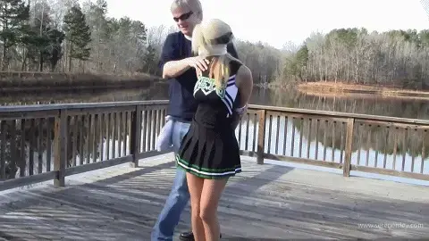 410 Holly Wood- The Cheerleader's Dock Dilemma 【中文seren】霍莉正站在码头上练习啦啦队动作，为即将到来的重要比赛做准备，这时一个男人走过来打断了她。她从专注练习和享受天气的状态瞬间被抓住，双臂被粗暴地用绳子捆在背后，肘部和手腕都受到限制。她大声呼救，但选了个太过偏僻的地方，根本派不上用场。男人捆好她手臂后，用红色布条堵住她嘴，又撕下白色微孔泡沫胶带，残忍地缠绕在她头部，将布条牢牢封在她嘴里。确信她现在安静多了，他继续往下，将她的脚踝紧紧捆在一起。摘掉她的眼镜后，他转身去检查准备好的卡车，打算将她装进去。最后男人折返回来，看着可怜的霍莉被捆在地面上的景象，放松了些，心里暗自得意。Holly was on the pier going over her cheer routine for the big game when a man came up and interrupted her with a bit of conversation. She goes quickly from practicing and enjoying the weather to getting grabbed and her arms roughly bound behind her back at the elbow and wrist. She cries for help but has picked entirely too secluded a location for it to do any good. After getting her arms bound he XXXX her to the ground and stuffs her mouth with a red cloth grabbing some white microfoam tape and cruelly wrapping it around her head sealing her gag tightly in her mouth. Confident she'll now be much more quiet he goes down to her ankles and binds them tightly together. Relieving her of her sunglasses he walks away to check the van he has ready to load her into. Finally the man comes back and relaxes a bit with the view taunting poor Holly as she stays bound and seated on the ground. 
