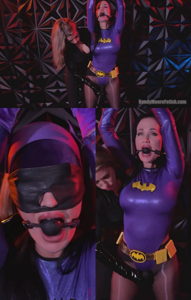 No Mercy For Batgirl 身着黑色紧身猫女装、束身胸衣和漆皮长靴的恶女兰迪·摩尔，将无助的蝙蝠女侠吊了起来，任她摆布。安吉拉被蒙住双眼，嘴里塞着球形口塞，身体无助地悬在半空，披风也抵挡不住即将到来的折磨。<br><br>兰迪用力拍打着她裸露的臀部，以此来刺激她的俘虏，宣告这位战败的女英雄不会被抛弃，她将被改造成自己最新的玩物。<br><br>她带着残酷的快感，抚摸挑逗着蝙蝠女侠的每一寸曲线，撕扯着她的披风，嘲笑着她被压抑的抗议。<br><br>折磨愈演愈烈，兰迪用膝盖顶着安吉拉颤抖的大腿，拽着她的头发控制着她的一举一动。她将猎物转过身，熟练的手指滑入蝙蝠女侠的内裤，无情地刺激着她的阴部，直到一股羞耻的快感席卷而来。<br><br>内裤成了折磨的工具，被拉扯成卡裆，用来抽打阴部，摩擦她湿漉漉的阴户。<br><br>当口塞终于被取下时，兰迪只是用霸道的吻占领了她的嘴，同时隔着戏服揉捏她的乳房。<br><br>兰迪背对着镜头，掰开并摇晃着安吉拉的臀瓣，然后又狠狠地拉扯她的内裤，将布料紧紧地勒在她肿胀的阴蒂上。<br><br>更多的摩擦，更多的扯头发，更多的抽打。兰迪再次把她转过来，一只胳膊搂住蝙蝠女，另一只手隔着戏服抚摸她的阴部。安吉拉的臀部背叛了她，拼命地磨蹭着那些灵巧的手指，直到她被推到高潮的边缘。<br><br>女反派把一个嗡嗡作响的振动器塞进安吉拉的内裤里，贴着她跳动的阴部，然后离开去打个电话。<br><br>镜头环绕着饱受折磨的女主角，捕捉着她与无情震动抗争的画面。兰迪回来了，摘下她的眼罩，取出玩具……却只是继续对她进行折磨。<br><br>接下来是一连串令人难以承受的高潮。扯头发、揉胸、打屁股、扯内裤、挑逗的吻交织在一起，兰迪一边用言语羞辱着她的新奴隶。<br><br>安吉拉嘴里塞着东西，哀求道：“求求你……”兰迪只是大笑，命令她叫得更大声些，然后让她达到最后一次爆发式的高潮，精疲力竭地瘫倒在地，脸朝下呻吟着，紧紧地抓着她过度劳累的阴部。Villainess Randy Moore, clad in a skintight black catsuit, corset, and patent leather boots, has the helpless Batgirl suspended and at her mercy. Blindfolded and ball-gagged, Angela's body hangs vulnerable, her cape offering no protection against what's coming.<br><br>Randy livens her captive with sharp spanks across her exposed ass, announcing that this defeated heroine won't be left behind, she'll be converted into her newest pleasure toy.<br><br>With cruel delight, she gropes and teases every curve, tearing away Batgirl's cape while mocking her muffled protests.<br><br>The torment intensifies as Randy grinds her knee between Angela's trembling thighs, pulling her hair to control every movement. Spinning her prey around, she slides expert fingers into Batgirl's panties, delivering relentless pussy stimulation until a shameful orgasm rips through her body.<br><br>Panties become a tool of torment, pulled into wedgies, used for pussy spanking, and rubbed against her dripping cunt.<br><br>When the gag finally comes off, it's only so Randy can claim her mouth with dominant kisses while mauling her tits through the costume.<br><br>Rear-facing the camera, Randy spreads and shakes Angela's ass cheeks before delivering another cruel wedgie, pulling the fabric tight against her swollen clit.<br><br>More grinding, more hair pulling, more spanking. Randy spins her around again, wrapping an arm around Batgirl while the other hand works her pussy over her outfit. Angela's hips betray her, grinding desperately into those skilled fingers until she's edged right to the brink.<br><br>The villainess tucks a buzzing vibrator inside Angela's panties against her throbbing pussy before leaving for a brief call.<br><br>The camera circles the tormented heroine, capturing her struggle against the relentless vibrations. Randy returns, removes the blindfold, and extracts the toy...only to continue her torment directly.<br><br>What follows is a barrage of multiple, overwhelming orgasms. Hair pulling, breast groping, spanking, wedgies, and taunting kisses blend together as Randy verbally degrades her new slut.<br><br>Angela begs through her gag: "Please..." Randy only laughs, demanding she beg louder before driving her to one final, explosive climax that leaves her exhausted and weak on the floor, face-down and moaning, clutching her over-worked pussy.