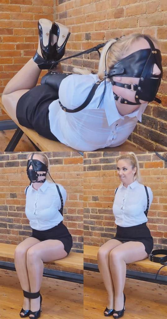 Lil Missy UK in Sirs Arm Binder And Hogtied Secretary Slave 米西身着笔挺的职业装，仪态万方，准备迎接每周的绩效考核，堪称一位尽职尽责的办公室奴隶的典范。她穿着经典的秘书制服，一件紧身的白色衬衫整齐地塞进黑色铅笔裙里，裙摆刚好遮住臀部。她双腿上穿着闪亮的肉色丝袜，在肌肤上熠熠生辉，一直延伸到锃亮的黑色高跟鞋。她花了一上午的时间精心布置老板的办公室，确保一切都完美无瑕，迎接这场“亲密的审视”。她深知这些考核对老板的重要性，也明白自己将如何被仔细审视、展示，甚至被束缚。<br><br>老板走进房间的那一刻，气氛瞬间从专业的氛围转变为充满侵略性的氛围。他一言不发，便开始有条不紊地将这位能干的秘书改造成一个顺从的办公室奴隶。首先是皮质臂套，这件残酷的装置将米西的双臂反绑在背后，紧紧的皮革包裹着她的手肘，从指尖到上臂，无一幸免。皮带的吱嘎声在寂静的办公室里回荡，他一一扣紧皮带扣，确保她上半身动弹不得，胸部挺起，撑破了白色衬衫的布料。<br><br>米西坐了下来，睁大眼睛看着老板跪在她面前，用一条厚厚的皮带缠住她的脚踝。她的双腿开始被束缚，黑色的皮带与她肉色的连裤袜形成鲜明的对比。他拉紧皮带，将她的双脚牢牢固定在一起，让她优雅的高跟鞋也无处可逃。她顺从地坐在那里，任由老板摆布。<br><br>接下来，她被戴上了皮质口塞。老板将橡胶球塞进她的嘴唇之间，然后将复杂的皮质口塞从她的头顶、下巴下方一直延伸到脸颊两侧。皮带扣咔哒一声扣上，撑开了她的嘴，唾液开始分泌。口水几乎要从她被束缚的嘴唇间流出来，口塞有效地阻止了她发出任何抗议或呻吟。为了彻底剥夺她的感官，加剧她的脆弱，一条黑色皮质眼罩蒙住了她的双眼，让她彻底陷入黑暗之中。<br><br>独自一人适应着这突如其来的现实，米西静静地坐在黑暗中，手臂束缚带让她呼吸困难。她只能听到自己压抑的呼吸声，以及偶尔从口塞处渗出、滴落在洁白衬衫上的口水。她无助而赤裸地等待着，焦急的等待与日俱增，她不知道老板何时会回来继续折磨她。<br><br>老板终于回来了，他没有丝毫犹豫。他抓住她被束缚的身体，把她放到长凳上，让她俯卧。坚硬的木板压着她的脸颊，她感觉到他在她身后忙碌着。他残忍地控制着她，将绳子系在口塞带上，然后向后拉，牢牢地固定在她的脚踝带上。捆绑完成——她的头被脚踝上的口塞狠狠地向后拉，背部弓起，下巴承受着巨大的压力，让她动弹不得。她只能忍受着，口水不停地流淌在身下的地毯上，穿着丝袜的双腿和高跟鞋毫无用处，双臂被束缚在身后的皮套里。<br><br>时间仿佛凝固，米西在严酷的捆绑中痛苦挣扎，肌肉因承受不住压力而开始颤抖。眼罩让她无法看到老板何时回来进行最后的考核。她感觉到老板的手粗暴地抓着她的衬衫，解开纽扣，露出她娇嫩的肌肤。冰冷的空气吹拂着她裸露的乳房，胸罩被推到一边，让她的双乳完全暴露在老板的审视之下。她的乳头在空气中挺立起来，或许是因为温度，或许是因为被彻底物化而产生的兴奋。<br><br>米西就这样静静地站在那里——完美地诠释了办公室服从的形象。她的衬衫敞开着，露出丰满的乳房，任由老板仔细审视。口水从她被堵住的嘴里源源不断地流出，汇聚在她脸下的长凳上。她每做一点点动作，皮质束缚带都会发出吱吱的响声，时刻提醒着她，她只不过是一件物品，任人检查、展示和使用。Missy stands poised and ready in her crisp professional attire, the epitome of a dedicated office slave preparing for her weekly performance review. Dressed in a classic secretary uniform, she wears a tight white button-up shirt tucked neatly into her black pencil skirt that ends just under her ass checks. Her legs are adorned with shiny nude pantyhose that shimmer against her skin, leading down to polished black high heels. She has spent the morning carefully arranging her boss's office, ensuring everything is perfectly for this intimate inspection. She knows how important these reviews are to her boss and how thoroughly she will be inspected, displayed, and restrained for this evaluation.<br><br>As her boss enters the room, the atmosphere shifts from professional to predatory. Without a word spoken, he begins the methodical process of transforming his capable secretary into an obedient office slave. First comes the leather arm binder, a cruel device that binds Missy's arms together behind her back, welding her elbows as the tight leather encases her limbs from fingertips to upper arms. The creaking of the straps echoes in the quiet office as he cinches each buckle, ensuring she has zero mobility in her upper body, her chest thrust forward, straining against the white fabric of her shirt.<br><br>Now seated, Missy watches with widening eyes as her boss kneels before her, wrapping a thick leather belt around her ankles. The restriction of her legs begins, the black leather contrasting sharply against her nude pantyhose as he pulls the belt tight, securing her feet together and rendering her elegant high heels useless for escape. She sits there obediently for her boss.<br><br>The next phase of her encasement involves a leather harness gag. Her boss places the rubber ball between her lips, strapping the intricate leather harness around her head, under her chin, and across her cheeks. The buckles click into place with finality, stretching her mouth open and causes saliva to begin forming. Drool already threatens to spill from her compromised lips as the gag effectively silences any protests or moans she might attempt. To complete her sensory deprivation and heighten her vulnerability, a black leather blindfold is secured over her eyes, plunging Missy into complete darkness.<br><br>Left alone to adjust to her new reality, Missy sits in silent darkness, her breathing restricted by the posture the arm binder places upon her. She can hear only her own muffled breaths and the occasional drip of drool escaping past the gag onto her pristine white shirt. The anticipation builds agonizingly as she waits, helpless and exposed, wondering when her boss will return to continue her submission.<br><br>When he finally returns, he wastes no time. Grabbing her bound body, he lays Missy down onto the bench, laying her on her front. The hard wood presses against her cheek as she feels him working behind her. In a cruel display of control, he ties rope to the harness gag strap and pulls them back, attaching them securely to her ankle belt. The hogtie is complete - her head pulled back harshly by the gag connection to her ankles, arching her back and putting immense strain on her jaw while keeping her completely immobilized on the floor. She can only endure, drooling continuously onto the carpet beneath her, her pantyhose-clad legs and high heels utterly useless, her arms trapped in the leather sleeve behind her.<br><br>Time stretches as Missy suffers in the strict hogtie, her muscles beginning to tremble from the strain. The blindfold prevents her from seeing when her boss finally returns for the final phase of her review. She feels his hands roughly grasping her shirt, undoing the buttons to expose her vulnerable flesh. The cool air hits her exposed tits as her bra is pushed aside, leaving her breasts fully displayed for his inspection. Her nipples harden in the open air, either from the temperature or her own arousal at being so thoroughly objectified.<br><br>There Missy remains - a perfect picture of office submission. Her shirt gapes open, revealing her tits for her boss's careful review. Drool streams steadily from her gagged mouth, pooling on the bench beneath her face. The leather restraints creak with every tiny movement she attempts, reminding her that she is merely property to be inspected, displayed, and used.