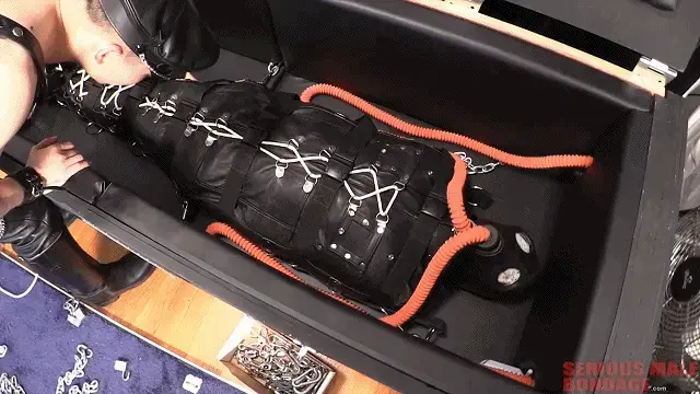 I Can't Escape Sir! 【中文】用一对橡胶软管连接到双缸起泡瓶。接着，他把男孩绑进一个皮睡袋里。然后，他使用Maxcita带子将睡袋固定在带衬垫的隔离箱内的连接点上。最后，他关上了盒子的顶部。盒子里的无线音频婴儿监视器允许雷监视他的儿子。最后，我们在婴儿监视器上听到了让整个过程变得值得的话：“我逃不掉，先生！”雷的工作完成了。Our friend Booted Ray from Recon is at it again. This time he puts his boy in a neoprene surf suit and gas-mask hood, which is then connected by a pair of rubber hoses to a dual-cylinder bubbler bottle. Next he straps the boy into a leather sleepsack. Then he uses a Maxcita strap set to secure the sleepsack to attachment points inside the padded isolation box. Finally he closes the top of the box. A wireless audio baby monitor inside the box allows Ray to monitor his boy. Finally, we hear over the baby monitor the words that make this whole process worthwhile "I can't escape Sir!" Ray's work is done.