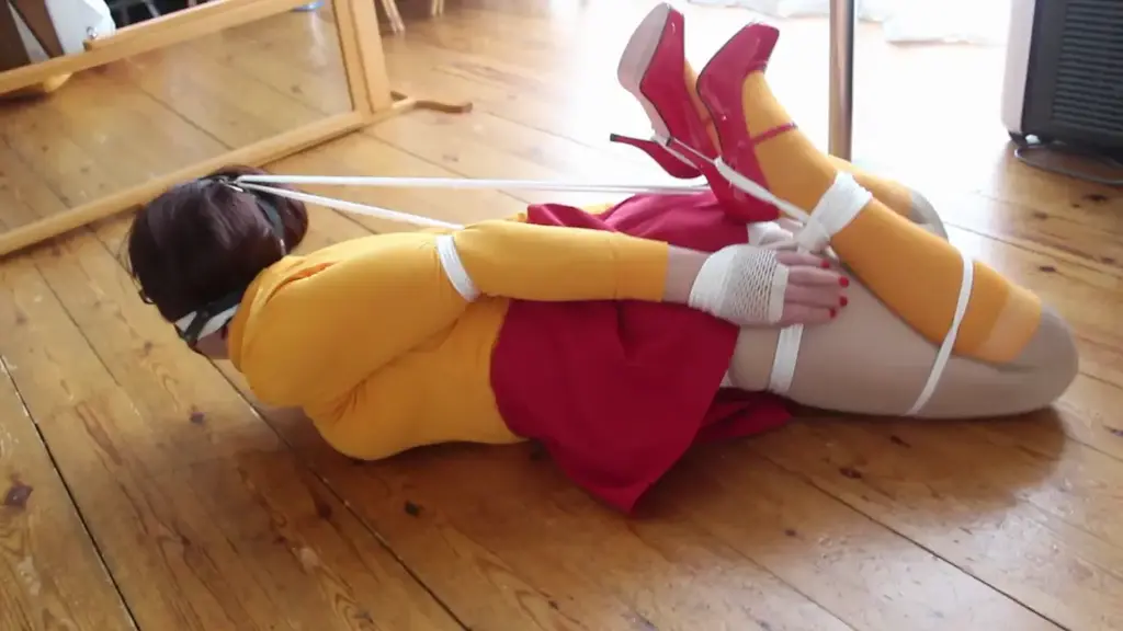 Jinkies Velma 伪娘<br>In the final Velma film. Nina has been put in a frogtie and still gagged with panties and tape and still flashing her own white panties she also has a head harness put on her so her head can be pulled back even tighter making it very hard to move or struggle 