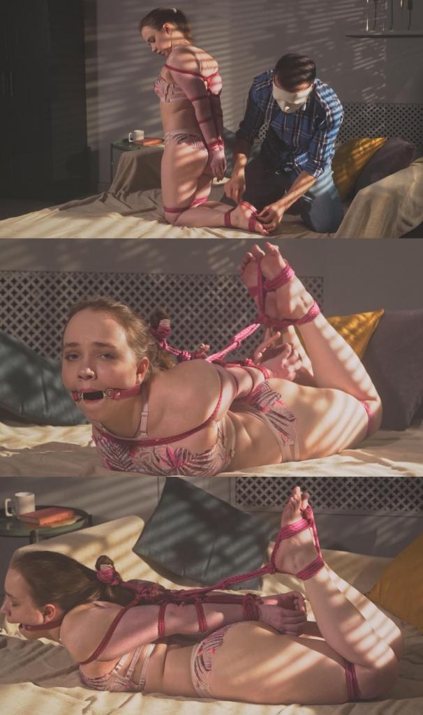 Arina - Sunrise Bondage - Tight Pink Rope Hogtie and Ring Gag for a Dream Cutie in Lingerie  阿丽娜坐在床上，穿着可爱的比基尼，一副清晨梦境中甜美可人的模样，准备接受束缚。<br><br>我走近她，开始用粉色绳子将她紧紧捆绑。先是她的双手被绑在背后，然后是双腿，绳子慢慢地将她原本柔美的睡颜变成了一幅严酷而美丽的束缚画面。<br><br>之后，我给她戴上口塞，让她趴下，继续捆绑，直到变成紧紧的猪蹄式捆绑。我用绳子缠住她赤裸的双脚，然后抬起并控制住她的头部，将她的头发向上绑起，完成了最后的姿势。<br><br>现在，阿丽娜被粉色绳子猪蹄式捆绑，嘴里塞着口塞，双脚被缠住，头被高高举起，独自一人静静地挣扎——为了她自己的愉悦，也为了你的愉悦。Arina is sitting on her bed, ready for bondage, dressed in a cute bikini and looking like a dreamy little morning fantasy.<br><br>I step closer and begin tying her tightly with pink rope. First her hands go behind her back, then her legs are secured, and the rope slowly turns her soft bedroom look into a strict, beautiful restraint scene.<br><br>After that I place a ring gag in her mouth and lay her down on her stomach, continuing the tie until it becomes a tight hogtie. I wrap her bare feet with rope, then lift and control her head by tying her hair upward, completing the final pose.<br><br>Now Arina is hogtied in pink rope, gagged, feet wrapped, head held up, and left alone to struggle sweetly - for her pleasure and yours.