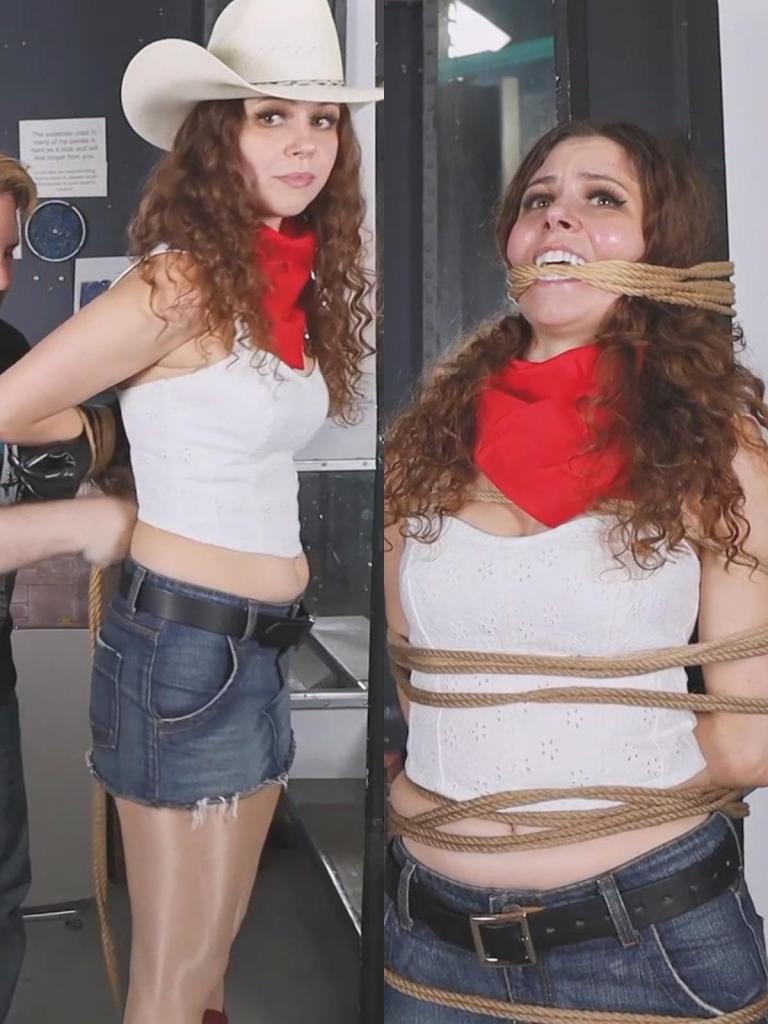 Cowgirl Mina MP4-Hot Cowgirl Mina Salome is bound to a post and gagged with rope 在一间光线昏暗、风格粗犷的牛仔酒吧里——空气中弥漫着浓郁的皮革气息——Mina Salome 优雅地将几束粗糙的黄麻绳递给了她的“俘虏”Hollyrope。酒吧的氛围融合了粗犷的魅力与俏皮的恶作剧色彩，背景中回荡着轻柔的乡村乐曲。Mina 身着一套勾勒出曼妙曲线的迷人装束，她缓慢而刻意地伸展着身姿，每一个动作都极具表现力，以此挑逗着围观者的目光。她那戴着手套的双手优雅而从容地置于身后，引人注目地突显出她那端庄的仪态。在画面中，她被绳索一丝不苟地捆绑成“箱式结”（boxtie），绳索紧贴着她身体的轮廓，勾勒出玲珑的曲线。场景切换至后半段，Mina 被牢固地捆绑在一根结实的木桩上，木材粗糙的质感与她光滑细腻的肌肤形成了鲜明的对比。随后，更多的绳索被巧手缠绕，形成一个紧实的口塞，封住了她的嘴唇，为这一刻平添了几分令人屏息的迷人张力。Mina Salome gracefully hands her captor, Hollyrope, several hanks of coarse jute rope at a dimly lit, rustic cowboy bar, where the air is thick with the scent of leather. The bar's ambiance is a blend of rugged charm and playful mischief, with soft country tunes echoing in the background. Mina, dressed in an alluring ensemble that hugs her curves, teases the onlookers with a slow, deliberate stretch, accentuating her every move. Her gloved hands, elegant and poised, are placed behind her back, inviting attention to her poised posture. On screen, she is secured in a meticulously tied boxtie, the rope snugly tracing the contours of her figure. In the second half, the scene shifts as Mina is firmly bound to a sturdy wooden post, the rough texture of the wood contrasting with her smooth skin. Additional rope is skillfully wound to silence her, forming a tight gag around her mouth, adding to the captivating tension of the moment.