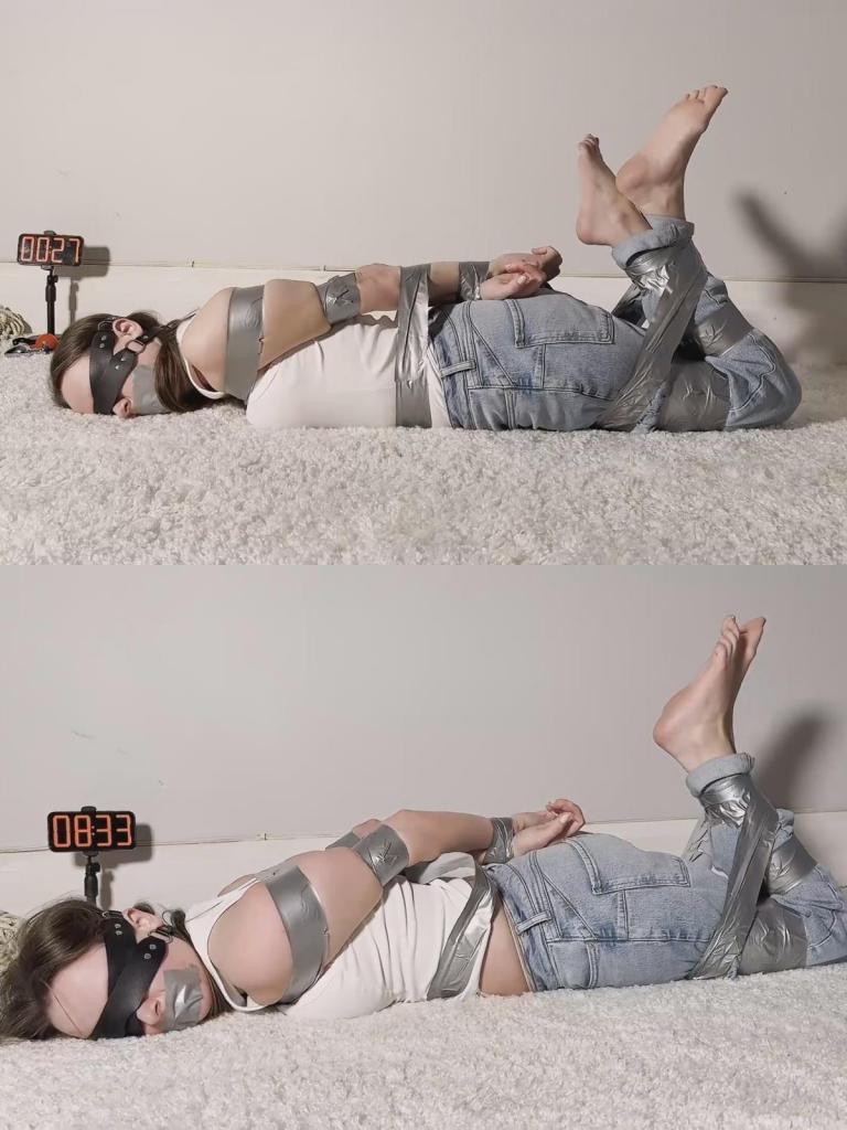 Bondage Escape Challenge - Duct Tape Hogtie 来看看我这段长达10分钟的束缚挣脱尝试：我被紧紧地用大力胶带捆绑，呈“猪蹄扣”（hogtie）姿势。一如既往，我的脚底和脚趾完全暴露在外；我被蒙住双眼，嘴上贴着胶带作为口塞，正奋力挣扎。每当我移动手臂，胶带就会压迫胸口，让我在被封住嘴的情况下呼吸变得更加困难。在试图挣脱双腿束缚的过程中，我的双脚随着腿部的动作不断扭动、屈伸。Watch my 10 minute bondage escape attempt, duct taped tight in a hogtie position. My soles and toes on full display as always, tape gagged, blindfolded and struggling hard. Every time I move my arms the tape presses against my chest, making it even harder to breathe through the gag. My feet wriggle and flex with my leg movements, while I try to free my legs