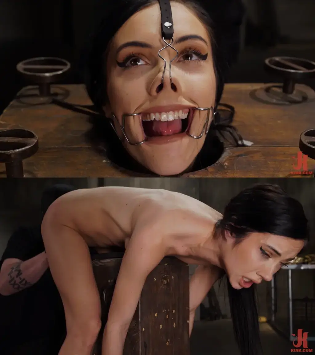 Fresh Flesh: Jazmin Luv Jazmin Luv is brand new to Kink, and The Pope is going to make a lasting impression on her for sure. She begins locked in a bondage cube with a neck stock to keep her secure. Her limbs are bound with leather straps. The process of disfiguring her face begins with one device made to stretch her mouth wide and anther to pull her nose back. In the next scene Jazmin is bent over a wooden post and secured with leather and steel shackles that hold her in a doggy position. She gets flogged on her exposed ass and then repeatedly hit with his hands to redden her ass properly. Next, The Pope introduces his cane and hits her legs, ass, and even her ribs. After proper torment, Jazmin’s face is stuffed with a massive dildo and she is throat fucked. Now with the dildo as wet as as her pussy, he shoves it deep inside her and fucks Jazmin’s pussy with it until she has multiple orgasms