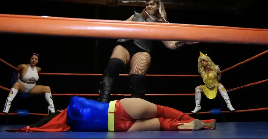 SUPERHEROINE AGENDA-UNCHAINED MALADY Part 3 of 4 Chapter Three: The quartet of heroines awaken after their individual defeats to find themselves each handcuffed to a ring post in a facsimile of the Arena of Champions. They are aghast to see their own dopplegangers standing triumphantly and sinisterly in the middle of the Arena as Dark Czar hovers above them, revealing his master plan of replacing each Sisterhood member with a Mime Replicant. As Dark Czar transports the duplicates out of the Arena, a sinister laugh rings out. As the light clears, the towering menace known as Malady (Saharra Huxly) appears, eager to indulge in her favorite pastime, destroying superheroines. She chooses to start with Compass (Kymberly Jane) as Daisy Chain (Stacy Burke), Prism (Jewell Marceau) and Sunburst (Angela Sommers) watch helplessly. Written and directed by George PÃ©rez.<br>第三章：四位女战士在各自战败后醒来，发现自己被铐在仿造的冠军竞技场的一根柱子上。她们惊恐地看到自己的复制体正得意洋洋地站在竞技场中央，而黑暗沙皇则盘旋在她们上方，揭示了他的宏伟计划——用一个模仿者复制体替换姐妹会的每一位成员。黑暗沙皇将复制体带出竞技​​场时，一阵阴森的笑声响起。随着光芒散去，名为“灾祸”（萨哈拉·赫克斯利饰）的强大威胁现身，她迫不及待地想要享受她最爱的消遣——摧毁超级女英雄。她选择从指南针（金伯莉·简饰）开始，而雏菊链（斯黛西·伯克饰）、棱镜（朱厄尔·玛索饰）和旭日（安吉拉·萨默斯饰）只能无助地看着这一切发生。本片由乔治·佩雷斯编剧并执导。