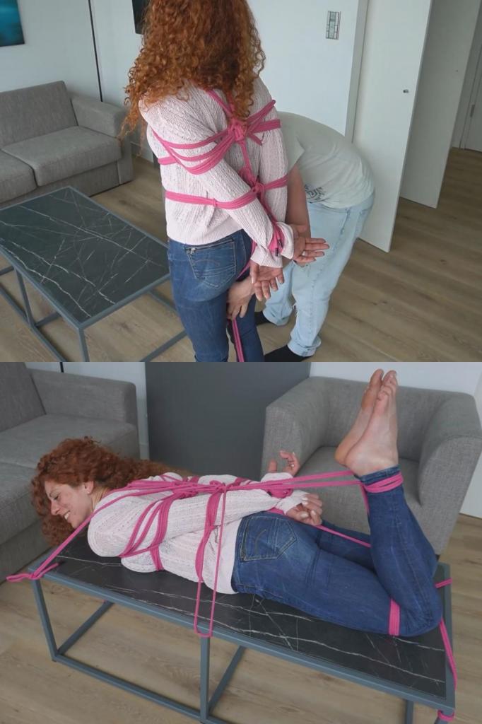 Lola Montez in "Hogtied &amp; Secured on the Table" 在一个阳光明媚的午后，温馨的客厅里，Lola 惬意地躺在那张宽大的黑色茶几上，脸上挂着调皮的微笑。她那头鲜艳的红色卷发如火红的瀑布般倾泻而下，发梢几乎触到了浅色的木地板。<br><br>她被柔软的亮粉色绳索以经典的“猪蹄扣”（hogtie）姿势轻轻却牢固地捆绑着。双手反绑在身后，脚踝被向上拉起，赤裸的双脚脚底俏皮地指向天花板。粉色绳索在她上半身缠绕出优美而均匀的纹路，既不显得过紧，又恰到好处地勾勒出她身穿宽松白色针织衫和紧身蓝色牛仔裤下的曼妙曲线。<br><br>这并非严苛的束缚，而是一场充满乐趣与友好的捆绑游戏……其中交织着欢笑、信任以及一丝令人心跳加速的兴奋感。Lola 双颊泛着淡淡的红晕，眼中闪烁着调皮的光芒，直视着镜头。她看起来毫无无助之态，反而显得快乐而自信，仿佛随时都会开口说道：“怎么样，你敢就这样把我多留一会儿吗？”<br><br>亮粉色的绳索与她白皙的肌肤及深色大理石茶几形成了绝妙的对比，柔和的日光投下轻柔的阴影，为整个画面营造出一种宛如油画般亲密而唯美的氛围。这是一幅展现俏皮顺从、轻松惬意与深厚友谊的画面……定格了那份源于彼此信任的纯粹喜悦。In the cozy living room on a sunny afternoon, Lola lay relaxed and with a mischievous smile on the large black coffee table. Her vibrant red curly hair cascaded like a fiery waterfall over the edge, almost touching the light wooden floor.<br><br>She was gently but securely bound in a classic hogtie with soft, bright pink ropes. Her hands were tied behind her back and her ankles drawn upward, so her bare soles pointed playfully toward the ceiling. The pink ropes wrapped around her upper body in beautiful, even patterns, accentuating her feminine curves beneath the loose white knit sweater and tight blue jeans, without being too tight.<br><br>It wasn’t strict bondage, but a playful, friendly bondage game... full of laughter, trust, and a touch of tingling excitement.Lola’s cheeks were softly flushed, her eyes sparkling cheekily at the camera. She didn’t look helpless, but happy and confident, as if she might say at any moment, “Well, do you dare to leave me like this a little longer?”<br><br>The bright pink ropes created a wonderful contrast against her fair skin and the dark marble table, while the soft daylight cast gentle shadows, giving the scene an almost painterly, intimate atmosphere.It was a picture of playful surrender, lightness, and deep friendship... a moment radiating pure joy in mutual trust.