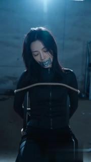 女特工被绑架挣扎1 一个身穿黑色衣服的女特工被绑在椅子上，双手背后五花大绑，双脚并拢捆绑，银色胶带封嘴，呜呜的叫着