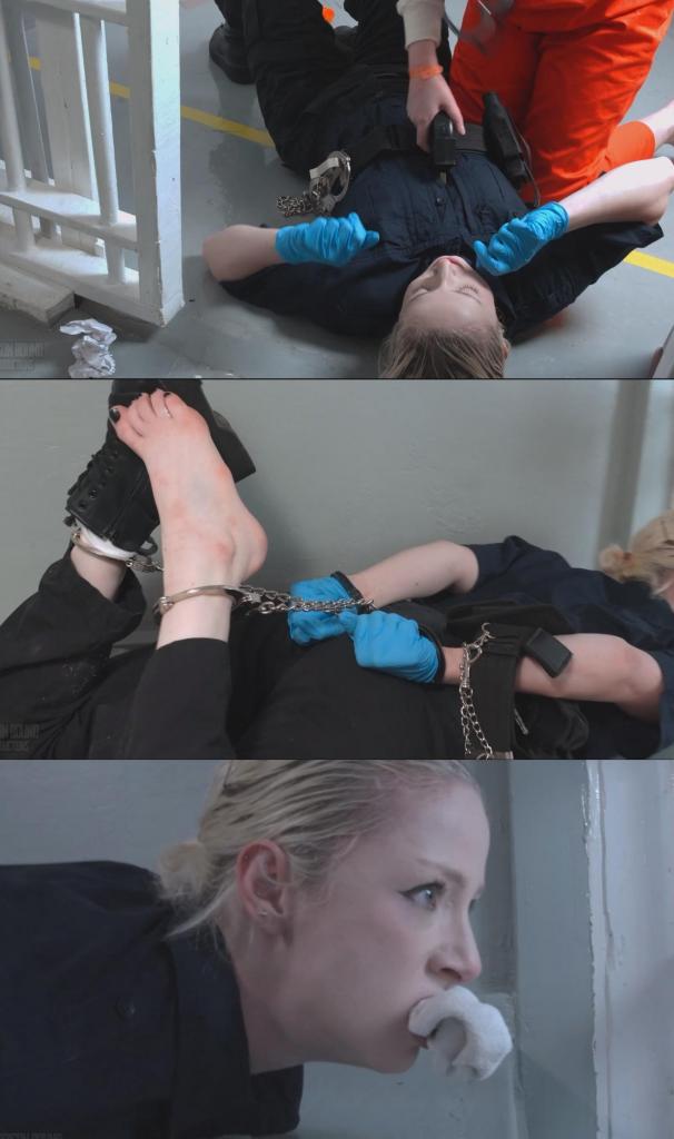 Jade's Prison Escape - Inmate girl gets her prison cell searched and overpowers her guard to re Jade's Prison Escape - Inmate girl gets her prison cell searched and overpowers her guard to reverse roles. Hog cuffed, shocked with handheld cattle prod, and mouth stuffed with sock for Officer Kora Summers 场景开始时，杰德正在牢房里写笔记本。她穿着一件橙色的连体囚服，里面套着一件监狱发的保暖内衣，脚上穿着橙色的袜子和拖鞋。<br><br>警官科拉·萨默斯走到牢房门口，命令杰德起来，过来戴上手铐。是时候搜身了，科拉确信杰德藏有违禁品。杰德被戴上手铐，双手抱头站在牢房后门，然后科拉打开门，命令她出来，靠墙站好。<br><br>科拉搜查了杰德的身体，脱掉她的鞋袜，检查她的脚趾缝。她什么也没找到，但确信杰德今天藏了什么东西。杰德被命令跪下，双手仍然被铐着，抱在头上。科拉命令她交叉裸露的脚踝，面朝墙壁，然后开始搜查牢房。<br><br>科拉把杰德的东西扔得满地都是，毫不留情地把她的物品一股脑儿地倒出来，大声朗读着笔记本上的私人段落，一边翻找着藏起来的东西，一边嘲讽着杰德，而杰德则毫不示弱地回击。<br><br>科拉在牢房里什么也没找到，但她并不满意。她再次进去搜查杰德，但放松警惕、低估了杰德的实力，却铸成了大错，让她丢了工作。杰德弯下腰，用手铐铐住科拉的头，然后猛地将她举过头顶，开始抚摸跪在地上的科拉。她用双臂勒住科拉的脖子，使出锁喉。科拉抓住杰德的头发，杰德则伸手去拿挂在科拉腰带上的电击棒。两人扭打在一起，在地上翻滚，杰德压在科拉身上，用电击棒抵着科拉的腹部。她命令她解开手铐，否则就电击她。科拉不情愿地照做了。<br><br>杰德挣脱了束缚，完全掌控了局面，她把狱警萨默斯推进牢房，电击棒抵着她的腰侧。她命令萨默斯躺在床上，然后把之前铐在科拉手腕上的手铐反铐在背后。杰德费了一番力气才解开科拉腰带上的镣铐，解开后，她拿起脚镣，脱掉科拉的一只靴子，用袜子堵住她的嘴，然后给她戴上紧紧的猪蹄式脚镣。她一边嘲讽科拉一边跑开了，科拉仍然被锁链束缚着，一只靴子被脱掉，嘴里塞着脏袜子，还在挣扎。<br><br>科拉挣扎了一会儿，杰德又跑了回来，一边说着“差点忘了东西”，一边扯下科拉的执勤腰带，拿走了她剩下的装备，更重要的是，还拿走了钥匙。然后她砰地一声关上牢房门，把科拉锁在里面，自己则跑开了，继续她的越狱之旅。<br><br>镜头继续聚焦在科拉身上，她吐出袜子，然后在床上翻来覆去地呼救，但似乎没有人来支援。她翻来覆去，好几次差点从床上摔下来。最后，一名男狱警终于来到牢房，发现了她这副狼狈的模样（这是以男狱警的视角拍摄的），他嘲笑她，说她肯定要被开除了。他说他要把她这样丢下，然后就走了，可能是去拉响警报，说有囚犯试图越狱。<br><br>The scene begins with Jade writing in a notebook in her cell. She's dressed in a snap button orange jumpsuit, with an authentic prison issue thermal under shirt, and some orange socks and slides to complete the outfit.<br><br>Officer Kora Summers walks up to the cell door and tells Jade to get up and come get handcuffed. It's time for a shakedown and Kora is certain Jade is hiding some kind of contraband. Jade is put in handcuffs and made to stand at the back of her cell with her hands on her head, then Kora opens the door and orders her out and up against the wall in the hallway.<br><br>Kora pats Jade down, and strips off her shoes and socks to check between her toes. She doesn't find anything but is convinced Jade is hiding something today. Jade is told to get down on her knees, hands still cuffed and on her head. Kora tells her to cross her now bare ankles and face the wall while she performs a cell search.<br><br>Kora tosses Jade's things around her cell dumping out her possessions without any care or delicacy, reading aloud private passages from a notebook journal, and tossing her mattress as she hunts for hidden items and taunts the prisoner, who responds defiantly.<br><br>There's nothing in the cell that Kora can find, but she isn't satisfied. She goes in to pat down Jade again, but letting her guard down and underestimating the prisoner turns into a mistake that will cost her job. Jade brings down her cuffed hands over Kora's head as she bends down to feel up the kneeling inmate. She wraps her arms around Kora's neck in a headlock. Kora grabs Jade by the hair, and Jade reaches for the hand held cattle prod holstered on Kora's duty belt. The two wrestle and tumble over each other on the floor with Jade landing on top holding the cattle prod to Kora's stomach. She tells her to unlock the cuffs or she will shock her. Kora begrudgingly complies.<br><br>Jade, now free of her restraints and fully in control of the situation pushes CO Summers into her cell with the electric prods pressed against her side. She orders her to lay down on the bunk, and she applies the handcuffs she had on earlier to Kora's wrists, cuffing her behind the back. Jade then struggles for a moment to get the shackles off of Kora's belt, but once she gets them free she takes the pair of leg-irons, removes one of Kora's boots, shoves a sock in her mouth to gag her, and then puts her in a tight hog cuff. She runs off taunting Kora, who remains struggling in chains, one boot off and with her dirty sock shoved in her mouth.<br><br>Kora struggles for a bit before Jade runs back in, "nearly forgot something" she says as she rips off Kora's duty belt taking the rest of her equipment and more importantly her keys with her. Then she slams the cell door shut locking Kora in and running away to continue her escape.<br><br>We stay with Kora who spits out the sock and then writhes around on the bed calling for backup that doesn't seem to come. She rolls around and nearly falls off the bunk a few times. When a male CO does eventually approach the cell and finds her in this predicament (seen as a POV from the male officer's view) he laughs at her at teases her saying she's definitely going to be fired. He says he's going to leave her like this, and walks off possibly to sound the alarm that an inmate is making an escape attempt.