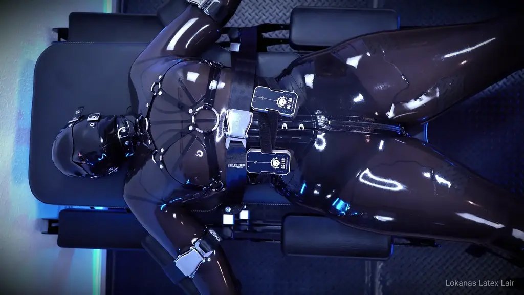Examination of a Latex Rubber Creature Enveloped in a latex sheet and fixed to the Hellcat examination table system, a rubber doll is examined and penetrated, helplessly at the mercy of the Rubber Doctor. Double-layer mask with a rebreather mask on top. Electro-stimulation pads under the catsuit.