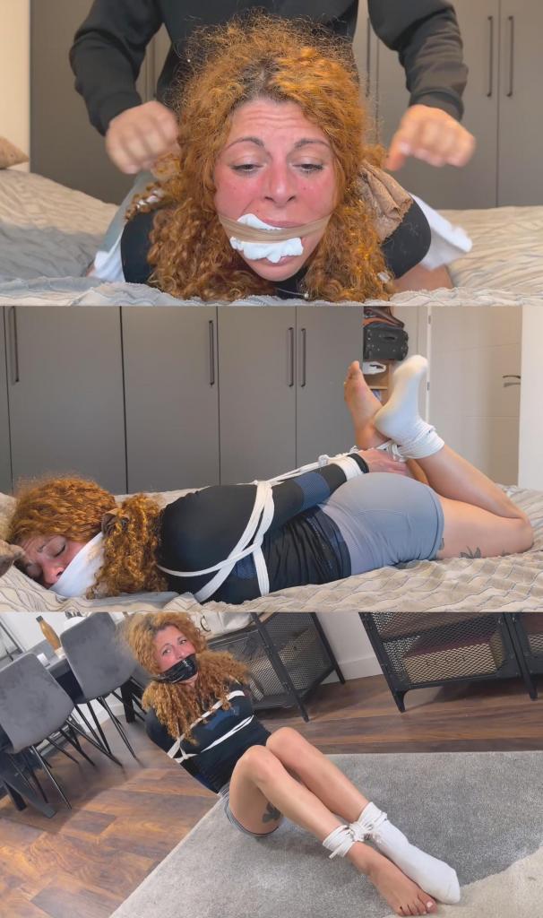 Lola – Home Invasion! Intruder Ties Her Up and Gropes Her 萝拉穿着紧身瑜伽短裤、合身长袖衬衫和白色船袜回家，完全没有意识到有个入侵者正在等着她。<br><br>他迅速制服了她，用绳子把她绑起来，用她自己的袜子塞住她的嘴，然后用胶带封住她的嘴。萝拉拼命挣扎，他则在她身上到处摸索，然后把她扛在肩上带进了卧室。<br><br>他把她扔到床上，没有堵住她的嘴，但没过多久，他又用她的白袜子塞住她的嘴，接着用丝袜勒住她的嘴，最后用一块白布堵住她的嘴。最后，他把她捆成猪蹄状，一边继续抚摸她，一边把她绑在床上无助地挣扎，然后扬长而去，留下她独自一人。<br><br>这是一个完整的DID场景，包含绳缚、多种口塞方式、挣扎、丝袜勒嘴、OTM口塞和最后的猪蹄状捆绑。Lola comes home wearing tight yoga shorts, a fitted long-sleeve shirt and white crew socks, completely unaware that an intruder is waiting for her.<br><br>He quickly overpowers her, ties her up with rope and uses her own sock as a mouth stuffing before securing a tape wrap gag over it. Lola struggles desperately while he gropes her all over her body, before he carries her over his shoulder into the bedroom.<br><br>He throws her onto the bed ungagged, but it doesn’t last long. Lola is soon gagged again with mouth stuffing using her white sock, followed by a stocking cleave and an OTM white-cloth gag. Finally, he puts her into a tight hogtie while he continues to grope her, leaving her bound and struggling helplessly on the bed before walking away and leaving her alone.<br><br>A full DID scenario with rope bondage, multiple gag variations, struggling, a stocking cleave, OTM gag and a final hogtie.