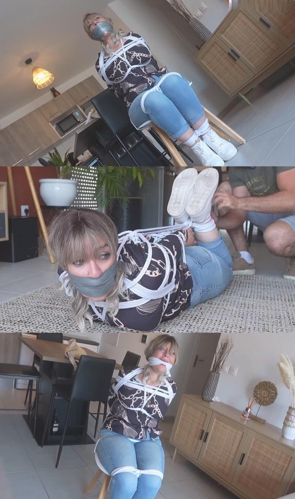 The French Girl - A Housewife Bound And Gagged 一位家庭主妇正准备出门办事。当她打开公寓前门时，却发现自己正面对着一个蒙面男子。男子一把将她推回屋内，捂住她的嘴，防止她尖叫或惊动邻居，然后迅速关上门。他紧紧抓住她，手仍然捂着她的嘴，把她带进厨房。在松开手之前，他命令她不许尖叫，并逼问她钱和其他贵重物品藏在哪里。他翻遍了她的手提包和家具，命令她待在原地，同时警惕地观察着她，以防她逃跑。<br><br>男子拿来一把椅子，命令女子坐下，然后开始将她牢牢地绑在椅子上。等她的双手被绑好后，他打算用厚厚的口塞彻底堵住她的嘴；女子的沉默让他感到安心，也让他不必再听她的抱怨。<br><br>女人最终被完全绑在椅子上：她的大腿、双腿、脚踝、双手和躯干都被牢牢地绑住；任何逃脱的尝试都是不可能的。她就这样挣扎呻吟了很久，而男人则在公寓里四处翻找。从房子的另一头，他听到女人的呻吟声越来越大。意识到邻居可能会听到动静，他决定采取行动。他取下她嘴里的布条；女人哀求他听她说，说她有话要说，但他没有时间浪费。他立刻用胶带紧紧地贴住她的嘴唇，让她瞬间哑口无言：“听我说……嗯 ...他回来后，撕掉了女人嘴上的胶带；女人立刻表示，只要他放了她，她就愿意说出所有东西的藏匿地点，并交出所有财物。说完后，她被绑了起来，跪在客厅中央；男人再次用胶带封住了她的嘴——这次是用一种叫做“口塞”的布条——同时核实她提供的信息。几分钟后，他回来了——不是为了解救她，而是为了确保自己能够逃脱，尽管她当时还不知道。他取下口塞，再次用胶带封住了她的嘴。女人可怜地呻吟着，但男人别无选择：否则，他一离开她就会报警。然而，她被捆绑着，嘴巴被层层胶带严严实实地封住，根本无法阻止他逃跑。可怜的女人的磨难远未结束；她随后被五花大绑。<br><br>临走前，他决定在她丈夫五个小时后回来之前给她一次解脱的机会……他把一把剪刀放在她面前。对这个女人来说，这并非真正的机会，而是可怕的挫败感。她反复挣扎，绝望地盯着面前的剪刀——眼中满是获得自由的渴望，尽管这显然是不可能的。嘴里塞着东西，无法发泄心中的挫败感，也无法动弹，这让她濒临崩溃！A housewife is getting ready to go out and run some errands. As she opens the front door to leave the apartment, she finds herself face-to-face with a masked man who shoves her back inside, clamping his hand over her mouth to prevent her from screaming or alerting the neighbors before quickly closing the door. He holds her firmly, his hand still over her mouth, while leading her into the kitchen. Before removing his hand, he orders her not to scream and demands to know where the money and other valuables are hidden. He rummages through her handbag and the furniture while ordering her to stay put, all the while remaining on guard in case she tries to flee.<br><br>The man returns with a chair he has found, orders the woman to sit, and begins tying her securely to it. Once her hands are bound, he intends to silence her completely using a thick gag; the resulting silence reassures him, sparing him from having to hear her complaints.<br><br>The woman ends up fully bound to the chair: her thighs, legs, ankles, hands, and torso are securely tied; any attempt to escape is impossible. She remains like this for a long time, struggling and moaning, while the man ransacks the apartment. From the other end of the home, he hears the woman's moans growing louder. Realizing the neighbors might hear the noise, he decides to act. He removes the gag; the woman begs him to listen, claiming she has something to say, but he has no time to waste. He immediately presses a strip of adhesive tape firmly over her lips, silencing her instantly: "Listen to me... MMMmmmhhhhhppphhhfffffmmmmmmm!" He wraps the tape tightly around her lips several times to seal them shut.<br><br>She is left to her futile struggles for a long while; unable to make a sound, she is at the mercy of the man, who takes his time.<br><br>Upon his return, he removes the tape from the woman's mouth; she immediately offers to reveal where everything is hidden and hand over all her possessions, provided she is set free. After speaking, she is bound and left kneeling in the middle of the living room; the man gags her again—this time with a cleave gag—while verifying the information. A few minutes later, he returns—not to free her, but to ensure he can make his escape, though she does not yet realize this. He removes the gag and uses tape once more to silence her. The woman moans pitifully, but the man has no choice: without this, she would raise the alarm the moment he left. However, bound as she is, with her mouth hermetically sealed by layers of tape, she cannot stop him from fleeing. Yet the poor woman's ordeal is far from over; she is then hogtied.<br><br>Before leaving, he decides to give her a chance to free herself before her husband returns in five hours... He places a pair of scissors in front of her. For the woman, this is not a genuine opportunity, but a source of terrible frustration. She struggles repeatedly, staring desperately at the scissors lying before her—her eyes wide with the hope of freedom, even though the task is clearly impossible. The inability to vent her frustration through the gag or move her body drives her to the brink of madness! 