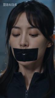 女特工被绑架挣扎2 一个身穿黑色特工服的女特工被绑在椅子上，双手背后捆绑，双脚并拢捆绑，黑胶带封嘴带封嘴，无助的四处观望着