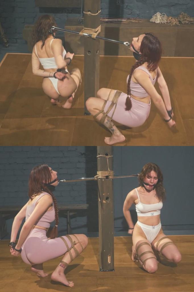 Bramble and Daria - Gagged and Rope-Tied Squat Challenge to the Music 在这段视频中，达莉娅和布兰布尔一起参加了一个荒诞的捆绑挑战。<br><br>两个女孩被以刻意设计的尴尬姿势捆绑在一起。首先，她们的双手被反铐在背后。然后，她们的双腿被绑成青蛙式，膝盖处弯曲，行动极其困难。<br><br>两位美女还被塞上了口球，戴上了项圈，项圈连接在同一根硬金属杆的两端，迫使她们的每一个动作都必须协调一致。<br><br>我扮演这场疯狂挑战的主持人，并解释规则：音乐响起后，达莉娅和布兰布尔必须蹲着移动，并尝试同时跳舞。<br><br>一旦挑战开始，就没有任何优雅的逃脱方法。<br><br>女孩们挪动着身子，弹跳着，努力保持平衡，试图在金属杆的束缚下，以同样的节奏舞动。任何人的尝试都会立即影响到另一人，最终将整个过程变成一场混乱的捆绑、协调、音乐和嬉戏竞争的混合体。<br><br>两位被堵住嘴巴、束缚住手脚的美女，一个金属连接器，以及一场极其滑稽的蹲舞挑战。In this clip, Daria and Bramble take part in a ridiculous little bondage challenge together.<br><br>Both girls are restrained in matching, deliberately awkward positions. First, their hands are secured behind their backs in handcuffs. Their legs are then tied in a frog-style position around the knees, making movement much more difficult.<br><br>Both beauties are also ballgagged and fitted with collars, and those collars are connected to opposite ends of the same rigid metal bar, making them to coordinate every movement.<br><br>I act as the host of this madness and explain the rules: as soon as the music starts, Daria and Bramble have to move around in a squat and try to dance at the same time.<br><br>And once the challenge begins, there is no graceful way out of it.<br><br>The girls shuffle, bounce, struggle to keep their balance, and try to move in rhythm while still connected to each other by the bar. Every attempt by one immediately affects the other, turning the whole thing into a chaotic mix of bondage, coordination, music, and playful competition.<br><br>Two gagged and restrained beauties, one metal connector, and one very silly squat-dancing challenge.