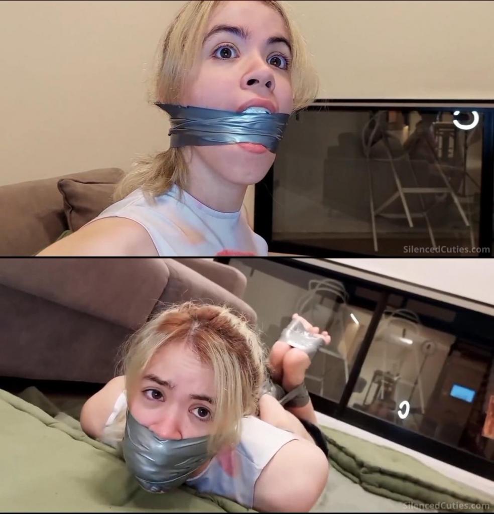 Too Much for Her Mouth?! Nani Left Topless and Gagged with Panties and Sock! Nani never imagined that after a day of training, she’d end up tightly bound with tape, her mouth completely stuffed with panties and a sock, sealed shut with tight tape, left topless, and with her underwear pulled down!<br><br>The adorable Nani returns home after an intense day of running and relaxes on the couch, unaware that a hidden intruder has been waiting for her just behind it. “Mmmmmpppphh!!!” Nani's cute mouth is firmly covered by the intruder's hand, and her arms are pinned as she struggles to figure out what’s happening. Well, Nani, you’re about to find out!<br><br>Nani is placed face down on the couch, and her hands are tied behind her back with layers of tape, wrapping them up completely like one big tape mitten! “What’s with all this tape?” wonders Nani curiously, not realizing this is only the beginning. Her cute legs are tightly bound together with even more layers, leaving her completely unable to continue her running routine. Then, the intruder brings a pair of panties he found nearby (they might not be clean) close to Nani’s face.<br><br>“That’s disgusting!” protests Nani as she catches the scent of the panties. The intruder rolls them into a ball and stuffs them into Nani’s mouth, pressing them in deeply to make sure her mouth is completely filled. “Mmmmmpppph!!” To keep the panties in place, he wraps several layers of tightly applied gray PVC tape over her open mouth, leaving her adorably gagged.<br><br> Nani is left alone and begins hopping around the house, searching for something to free herself. Unluckily (or rather, luckily!), she doesn’t find anything!<br><br>At that moment, the intruder captures Nani again, throws her over his shoulder, and places her on the floor. Nani has been far too noisy, and it’s time to silence her even more! He removes the socks from her cute feet (how do they smell?) and uses one to stuff it into Nani’s already filled mouth, packing it even tighter, before sealing her lips completely with numerous wraps of tape from her chin to just under her adorable nose<br><br>