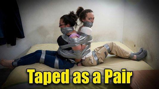 Taped as a Pair, They Stayed Right There Taped as a Pair, They Stayed Right There<br><br>Laura and Graciela are waiting to surprise Maia when she gets home. The moment she walks through the door, they grab her. Maia doesn’t resist much - she even seems to enjoy it.<br><br>Laura quickly tapes Maia’s wrists behind her back and her ankles while Graciela keeps a hand over her mouth. They stuff a pair of socks into Maia’s mouth and wrap duct tape tightly around her head several times. Graciela then throws Maia over her shoulder and carries her into the bedroom, with Laura giving her several spanks along the way.<br><br>Once in the bedroom, they finish taping the rest of Maia’s body and leave her alone to try and escape. Maia squirms and struggles playfully on the bed but can’t get free.<br><br>When Laura and Graciela return, they tease her for failing. That’s when Graciela gets confident and tells Laura to tape her up the same way - she’s sure she can escape easily. Laura accepts the challenge and tapes Graciela’s wrists, ankles, and body, stuffs two socks in her mouth, and wraps duct tape around her head.<br><br>After watching Graciela struggle and fail as well, Laura sits both girls back-to-back on the bed and tapes them together tightly. She squeezes both of their gags, kisses them goodbye, and leaves them there.<br><br>Maia and Graciela spend the rest of the video squirming and talking to each other through their thick tape gags, completely stuck as a pair.<br><br>Included in this clip: back to back taped, duct tape bondage, sock gag, tape gag, playful bondage, two girls taped, taped together, back to back bondage, sock stuffed mouth, tape wrapped head, playful struggling, friends bondage, duct tape escape, taped as a pair, gag talking, light bondage, stuck together, back to back gag, tape challenge